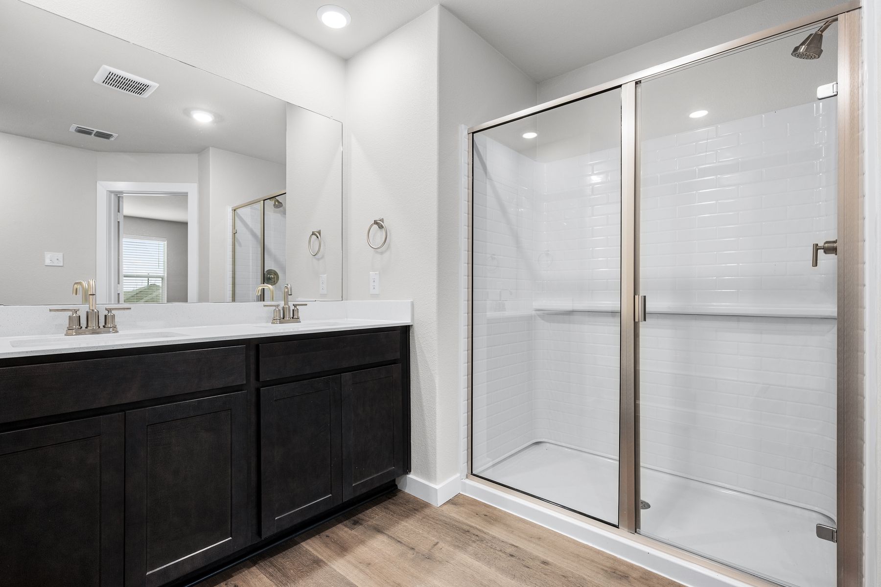 The master bathroom has a sprawling vanity and glass, walk-in shower.