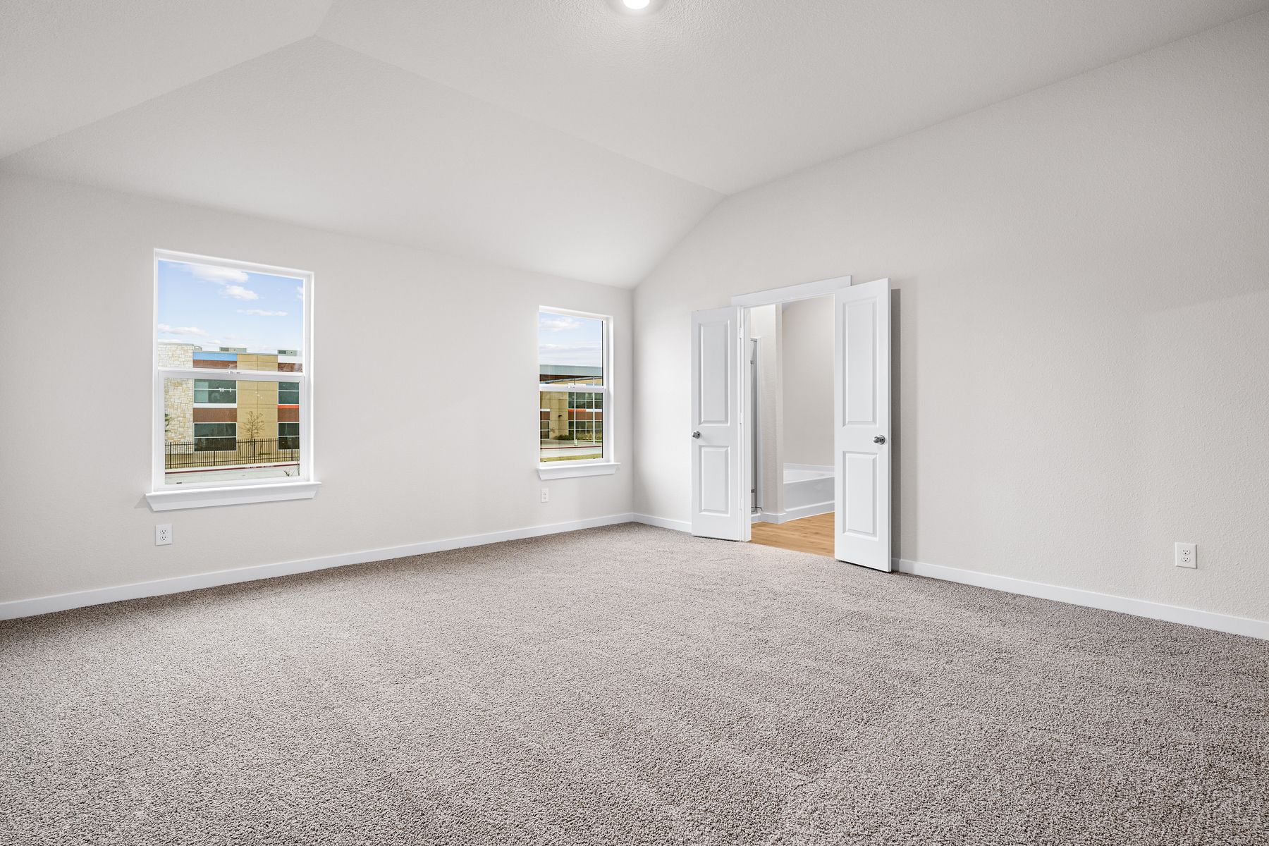 The master bedroom is spacious and has two large windows.