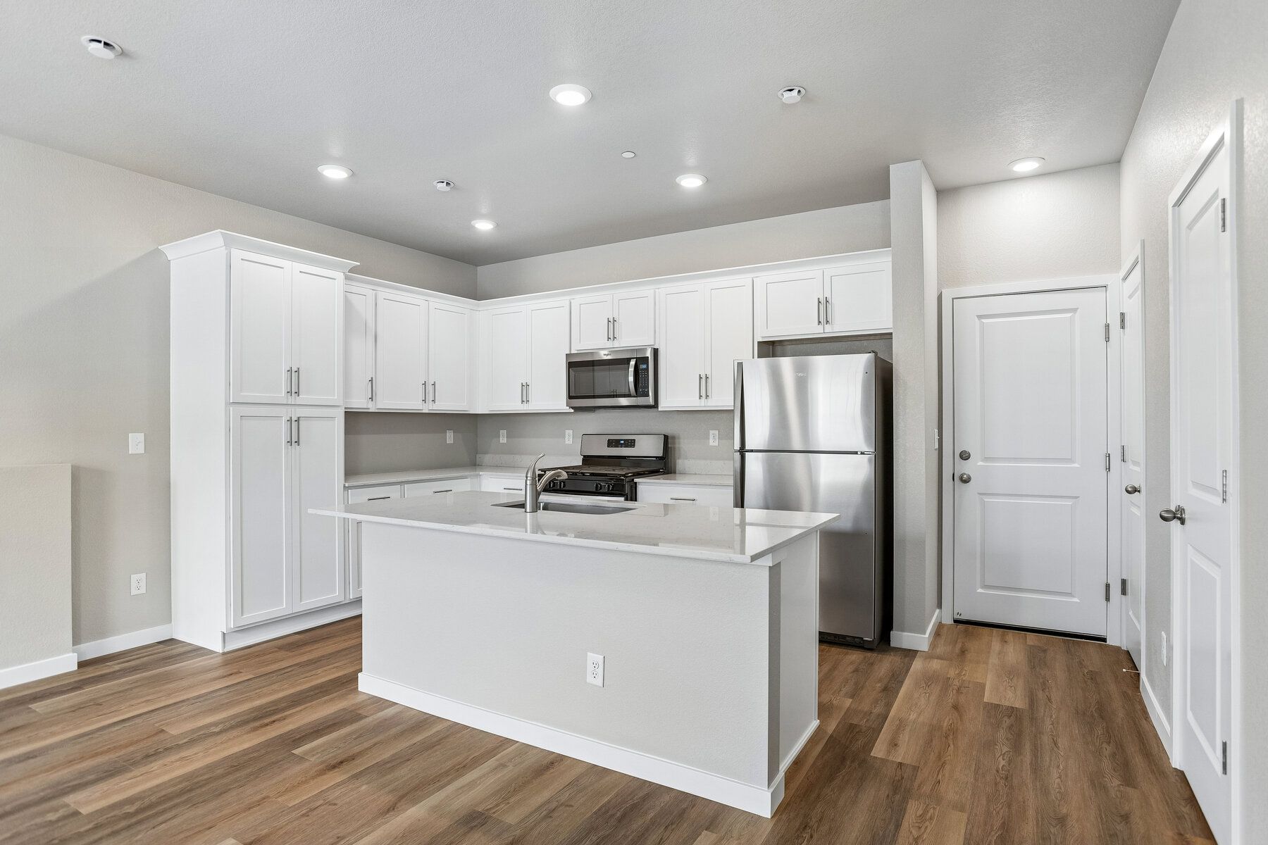 The kitchen has stainless steel appliances and plank flooring.