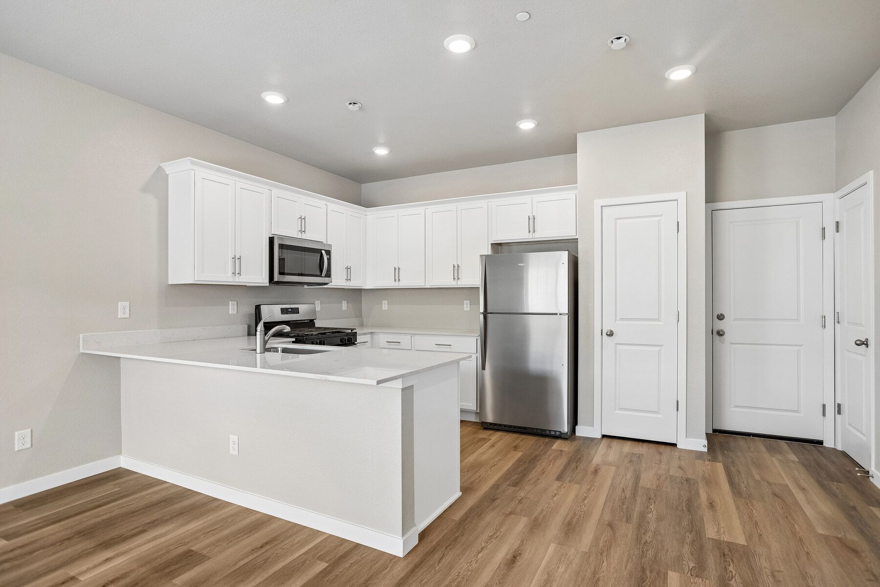 The kitchen has stainless steel appliances and plank flooring.
