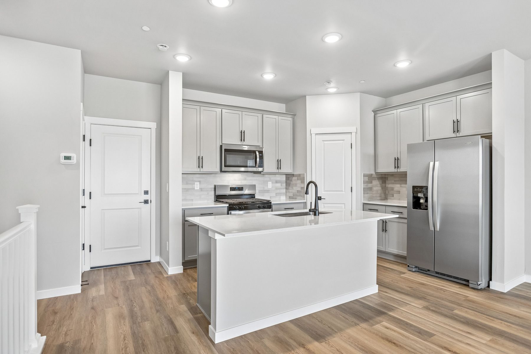 The kitchen has stainless steel appliances and plank flooring.