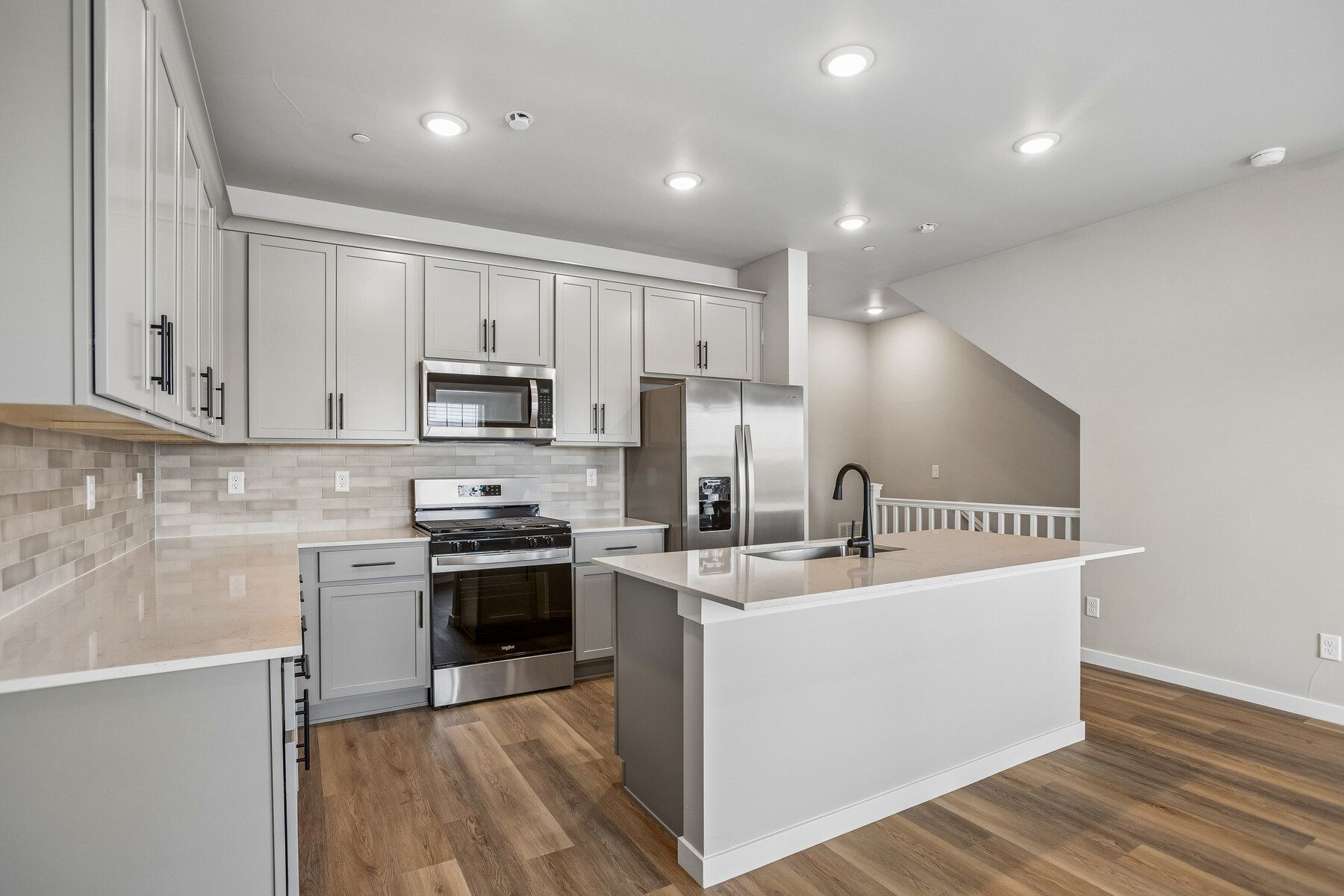 The kitchen has stainless steel appliances and plank flooring.