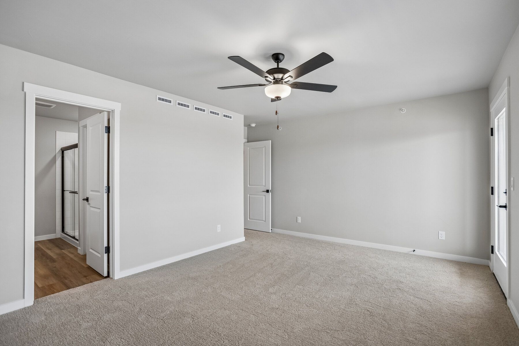 The master bedroom is spacious with a ceiling fan.