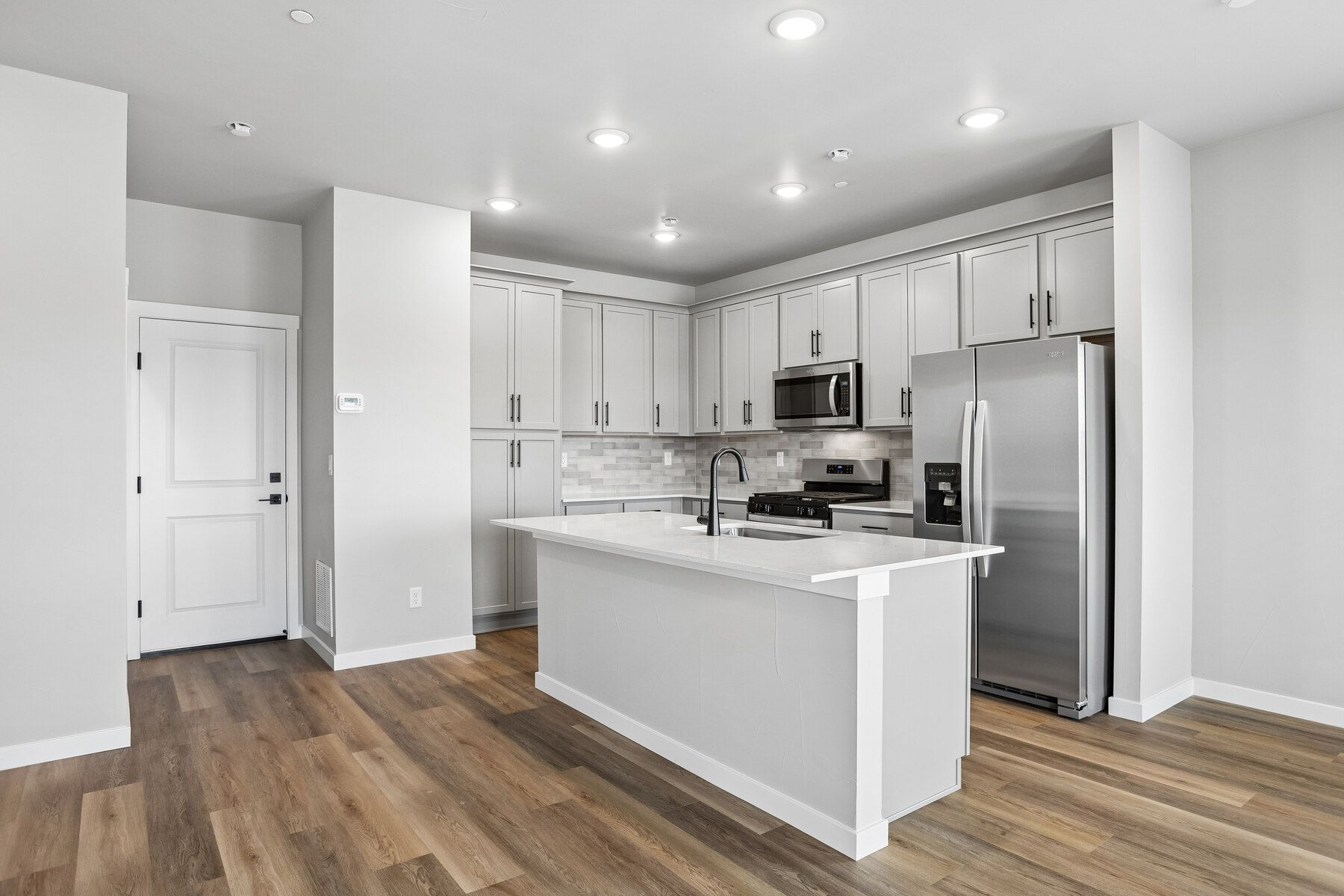 The kitchen has stainless steel appliances and plank flooring.