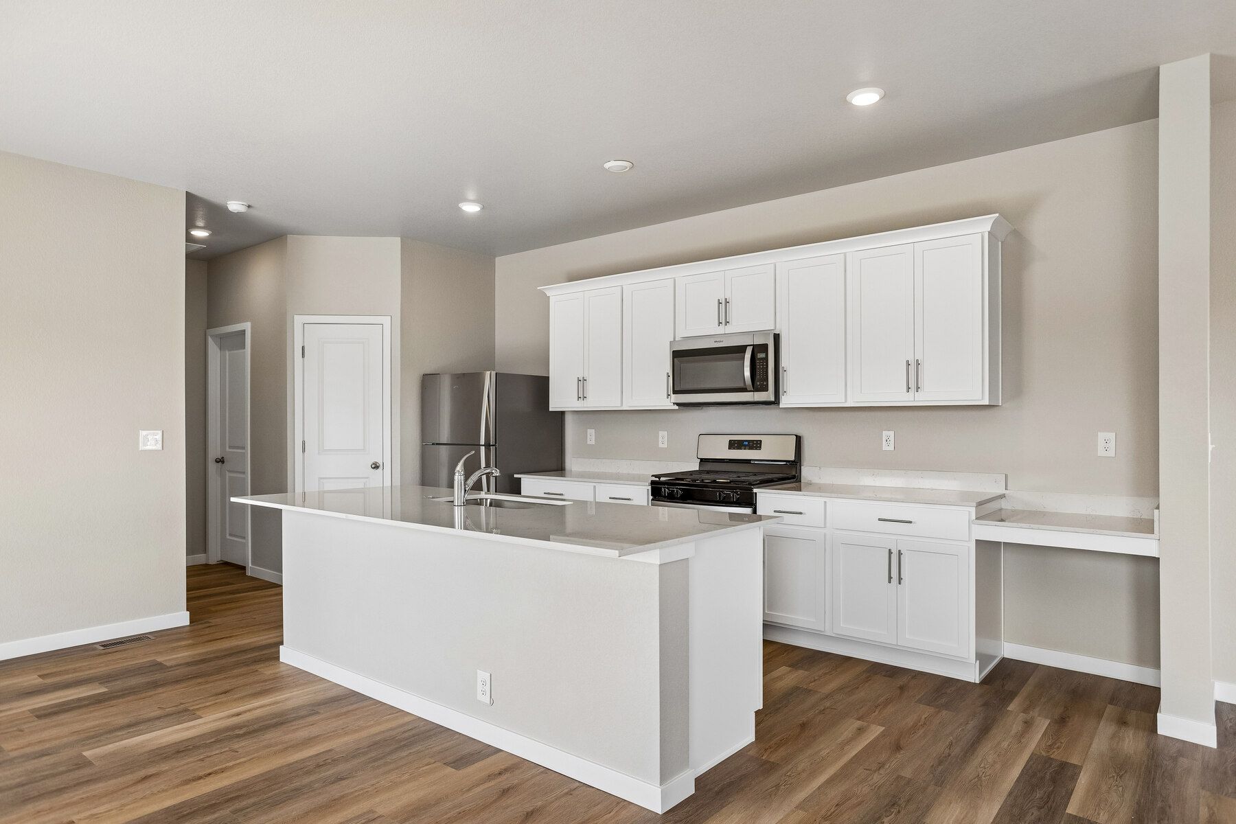 The kitchen has stainless steel appliances and plank flooring.