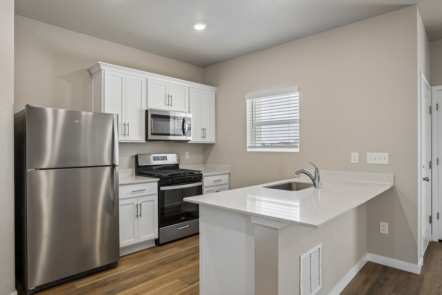 The kitchen has stainless steel appliances and plank flooring.