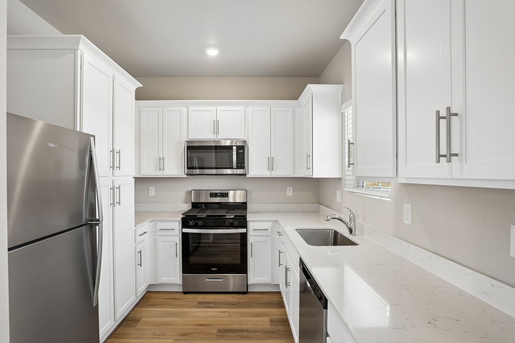 The kitchen has stainless steel appliances and plank flooring.