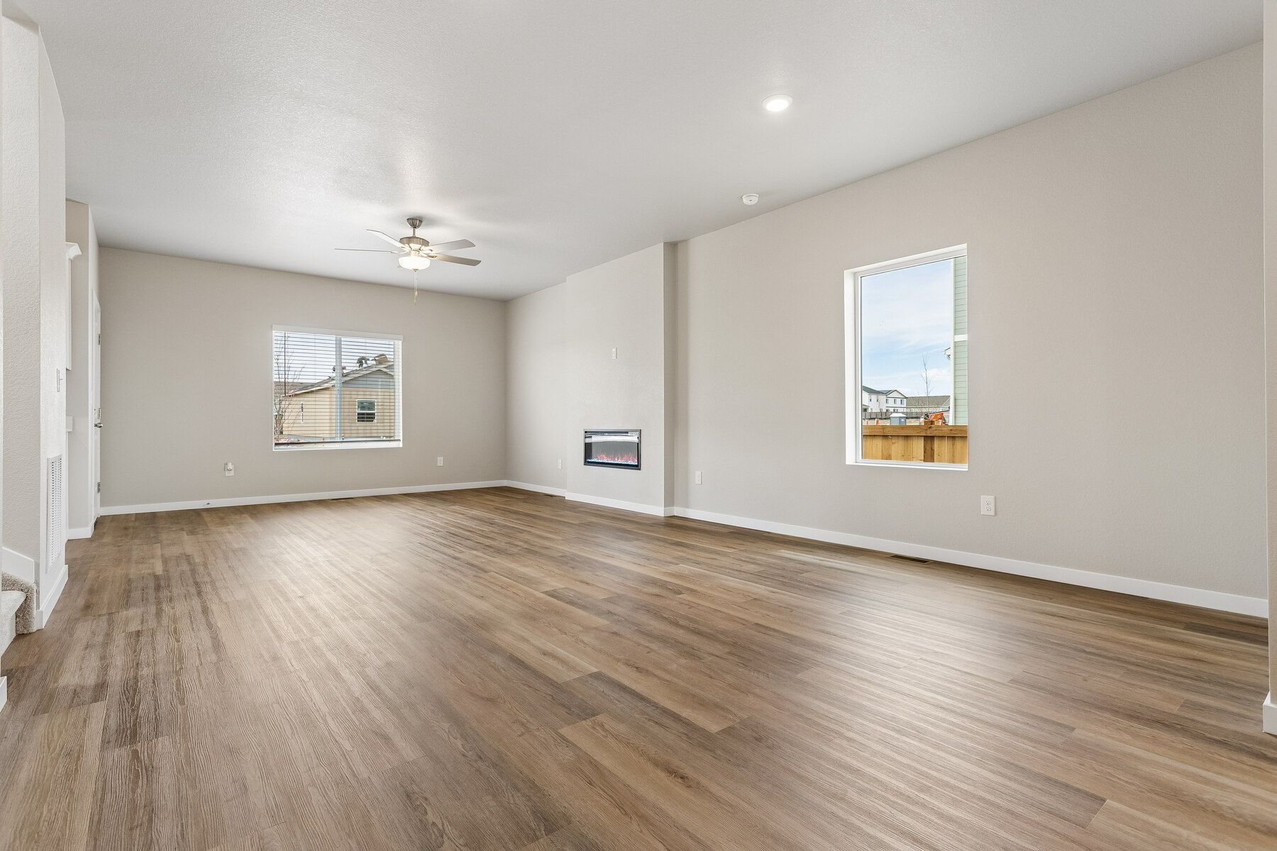 The family room is spacious with a ceiling fan and an electric fireplace..