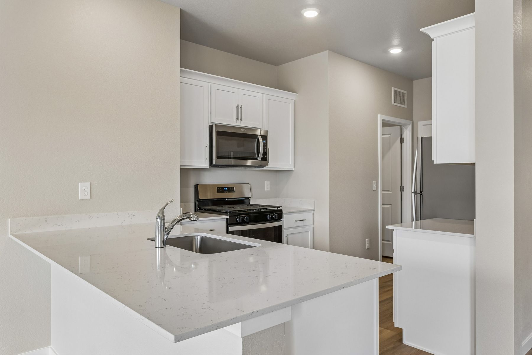 The kitchen has stainless steel appliances and plank flooring.