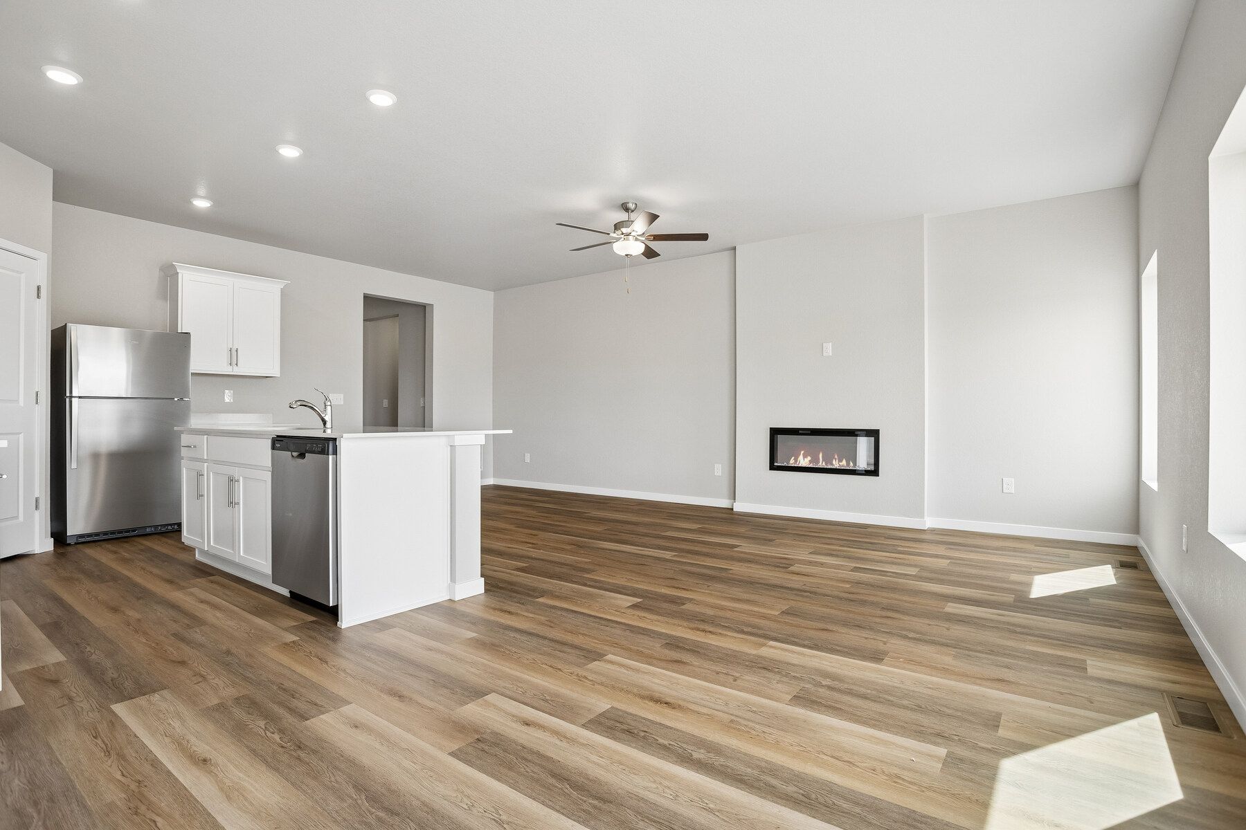 The family room is spacious and has a ceiling fan and an electric fireplace.