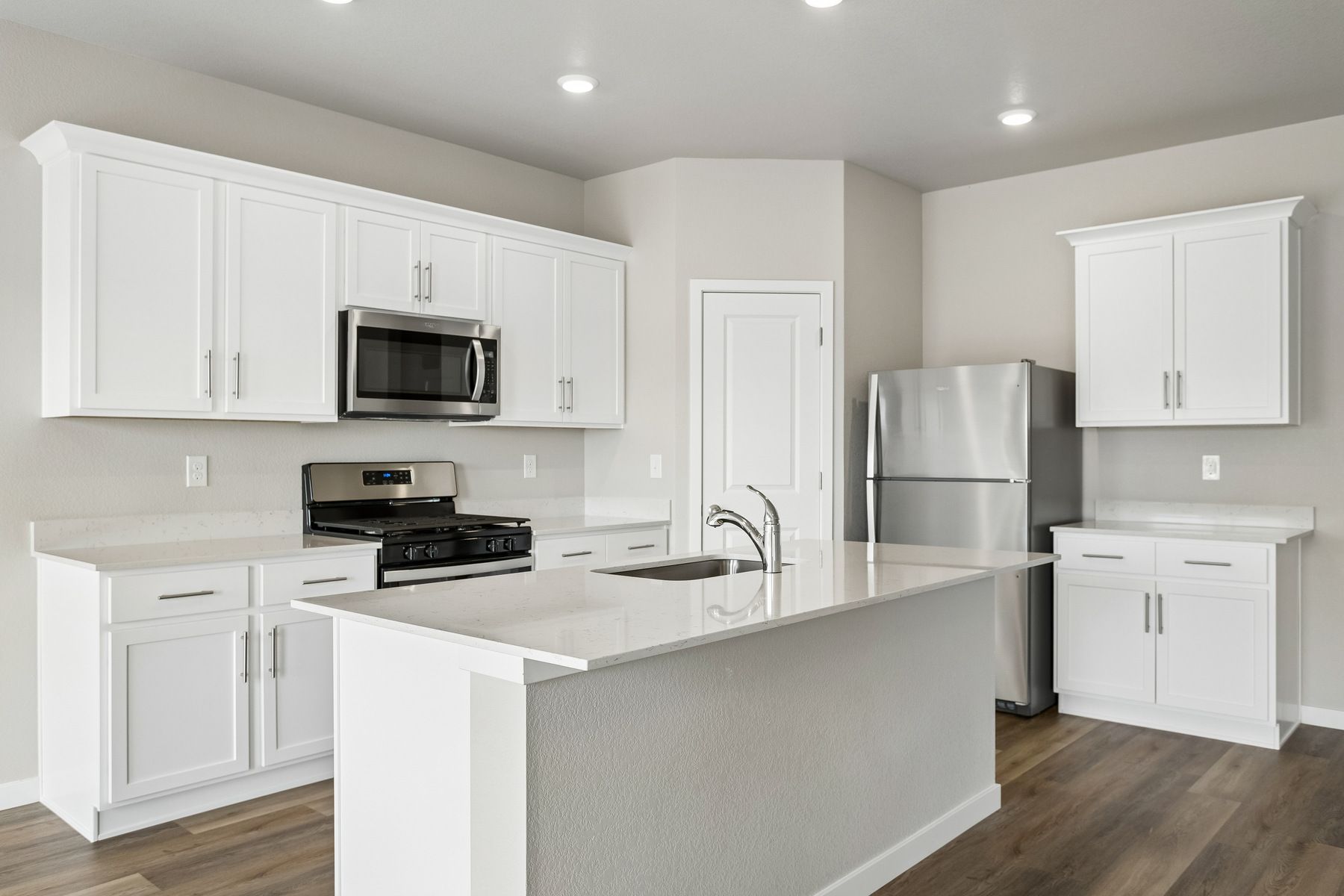 The kitchen has stainless steel appliances and plank flooring.