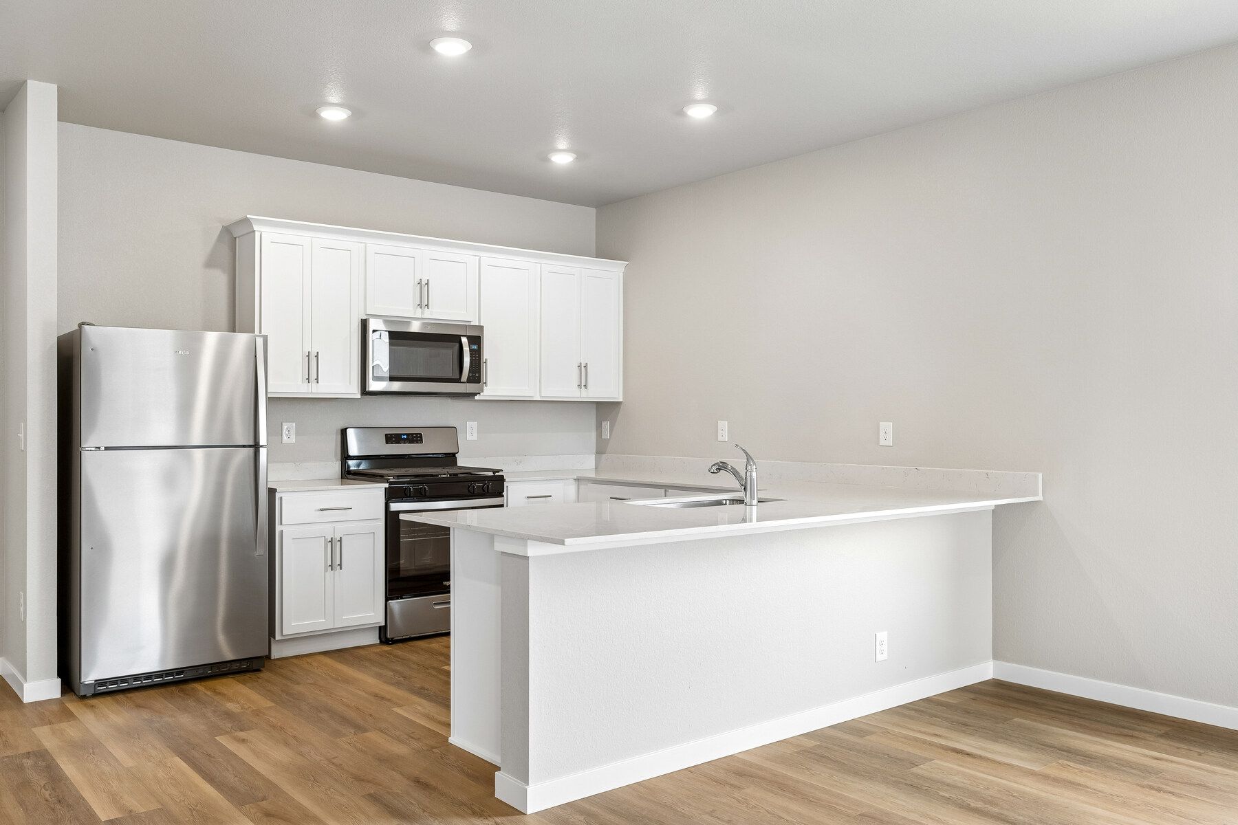 The kitchen has stainless steel appliances and plank flooring.