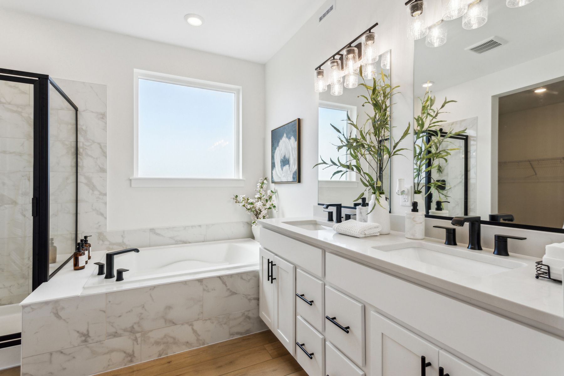 The master bathroom has a large vanity, garden tub, and glass walk-in shower. 