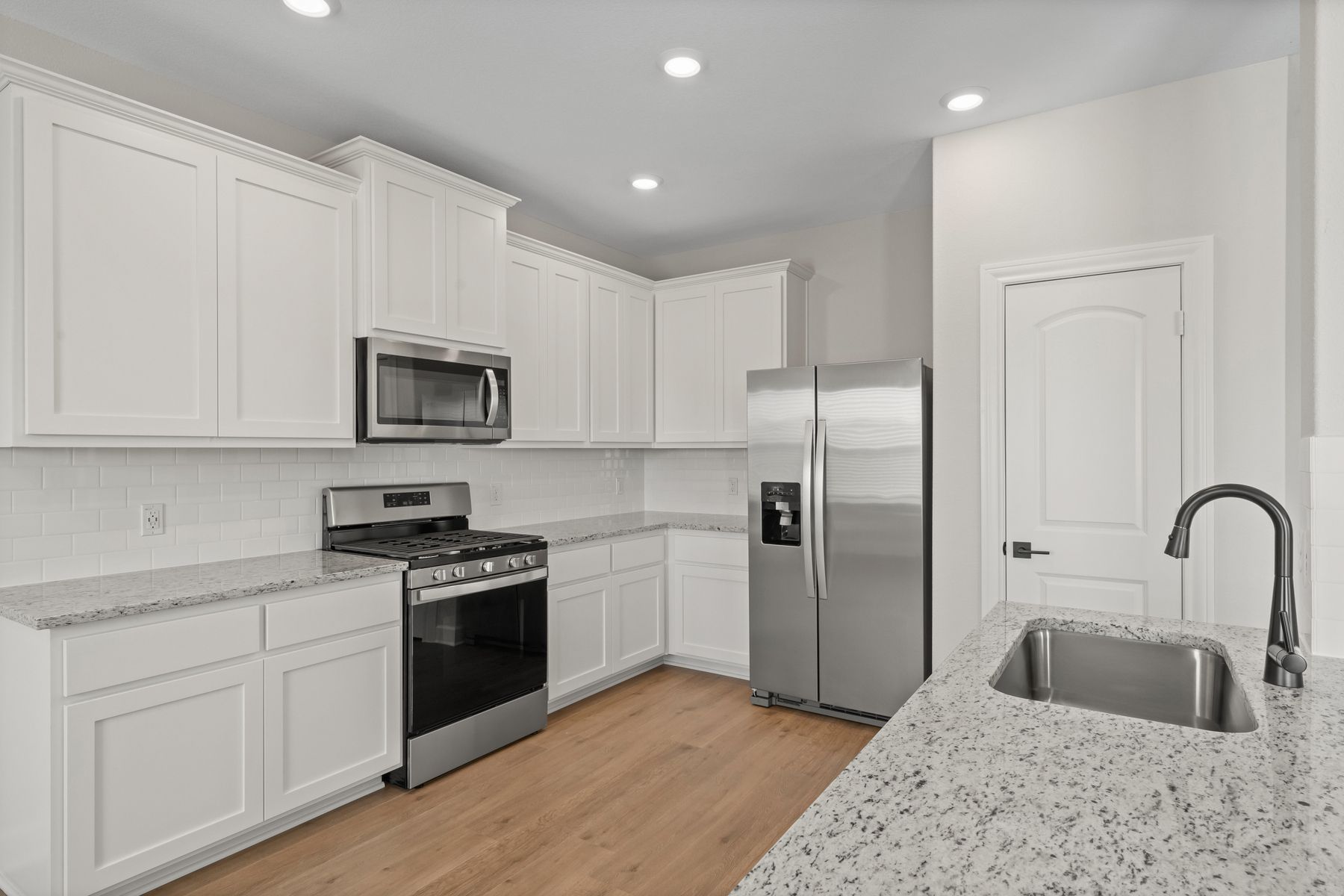 The kitchen has white cabinetry. 