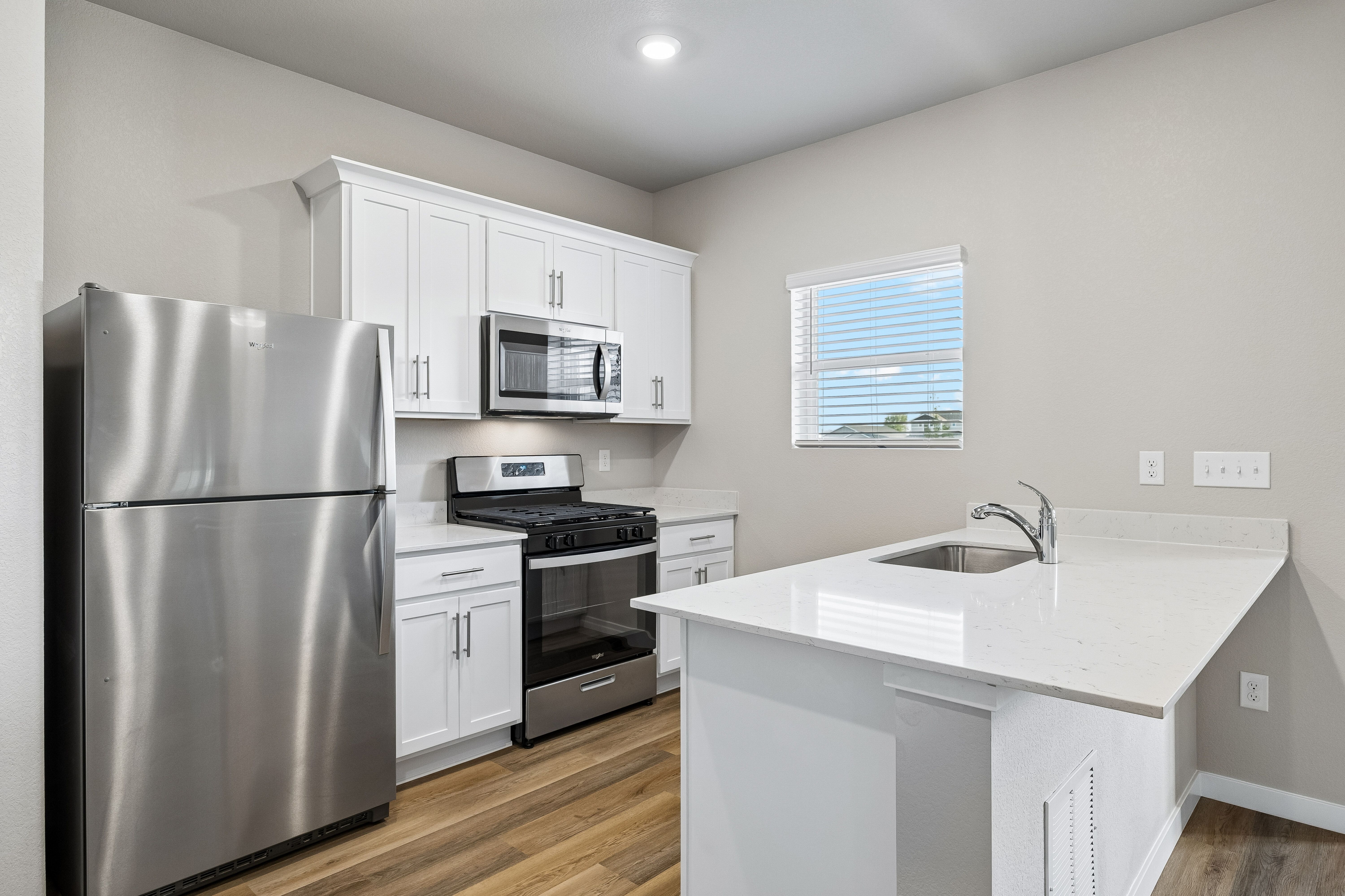 The kitchen has stainless steel appliances and plank flooring.