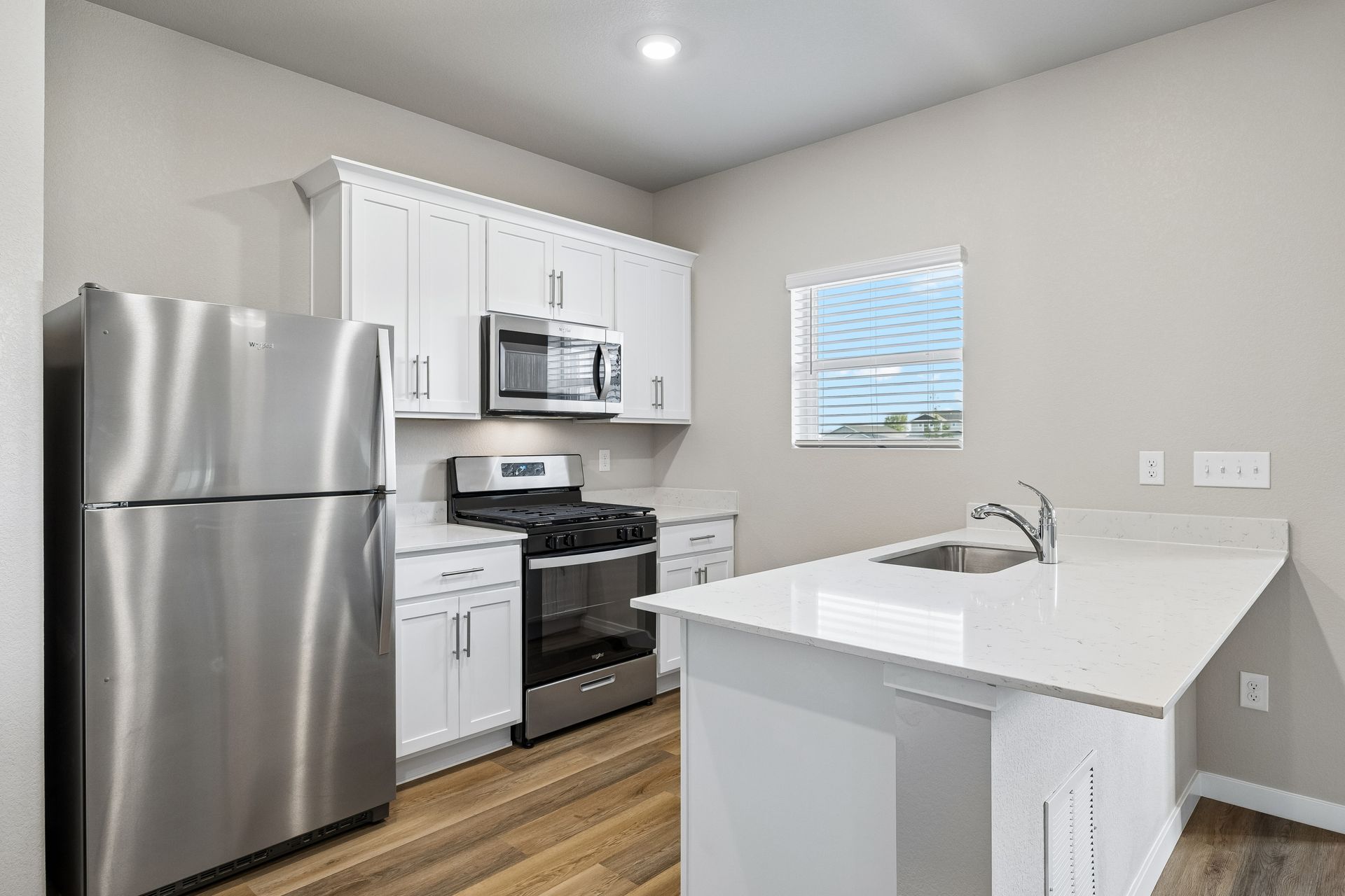 The kitchen has stainless steel appliances and plank flooring.
