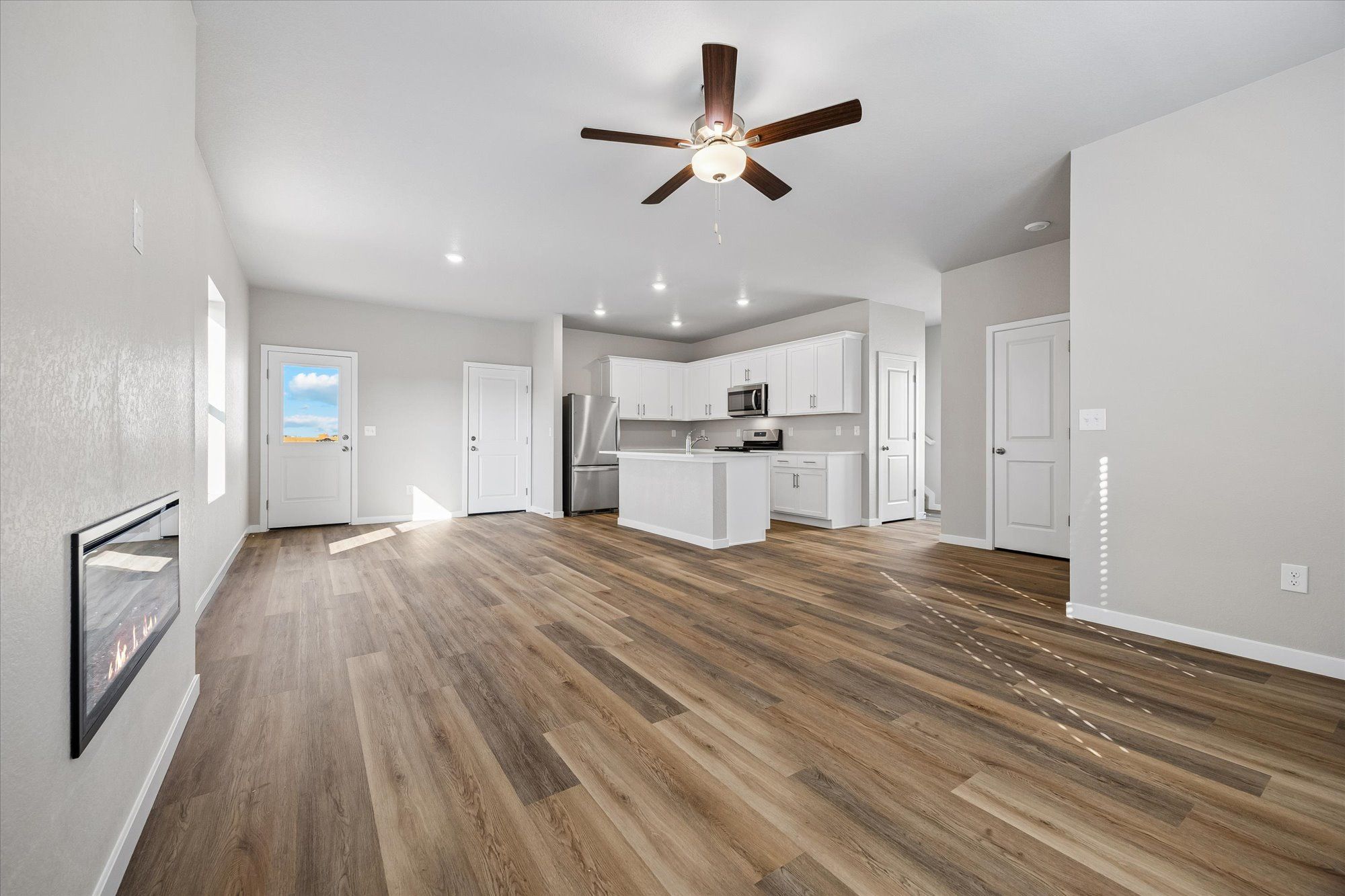 The family room is spacious with a ceiling fan and an electric fireplace.