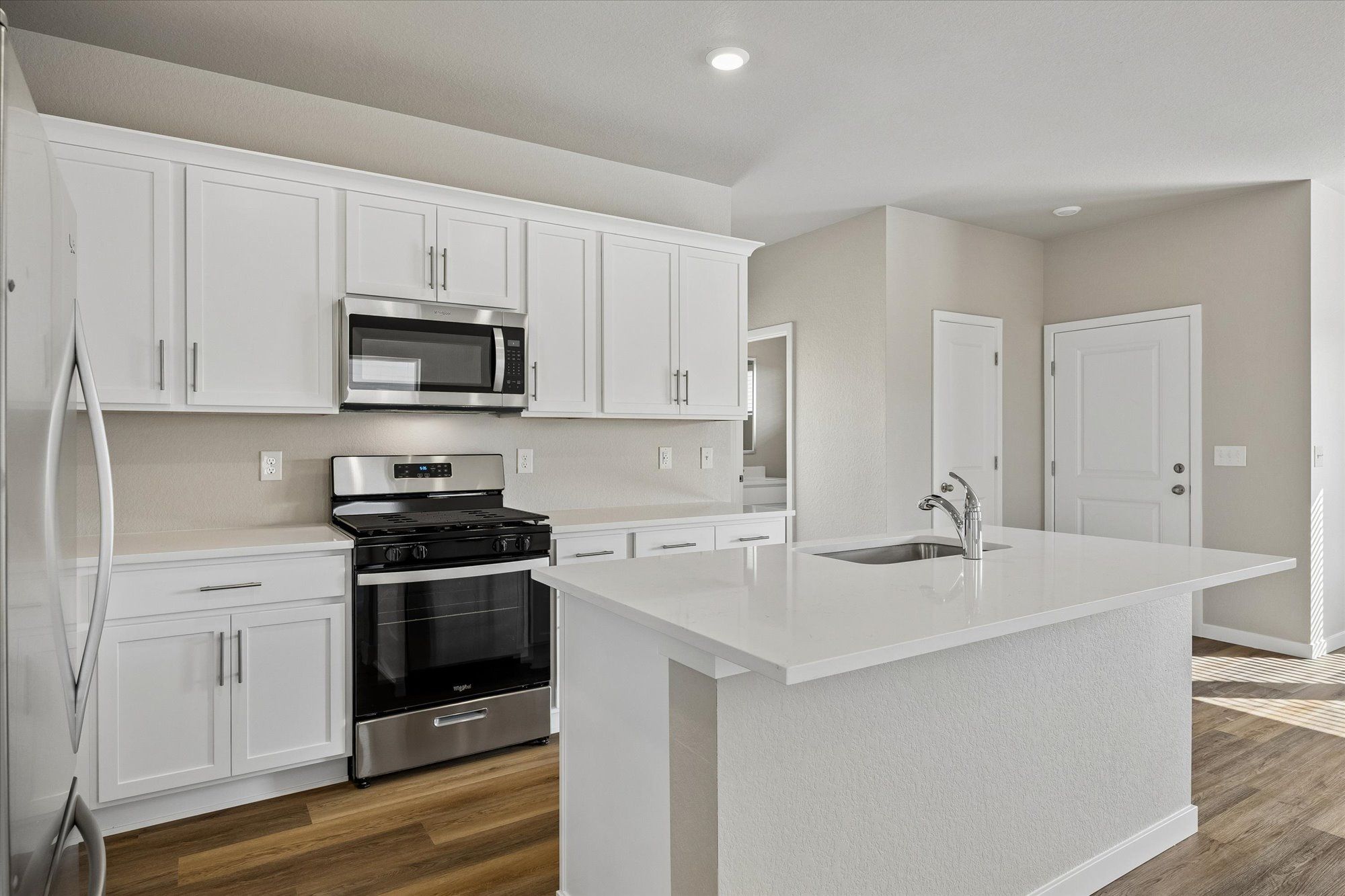 The kitchen has stainless steel appliances and plank flooring.