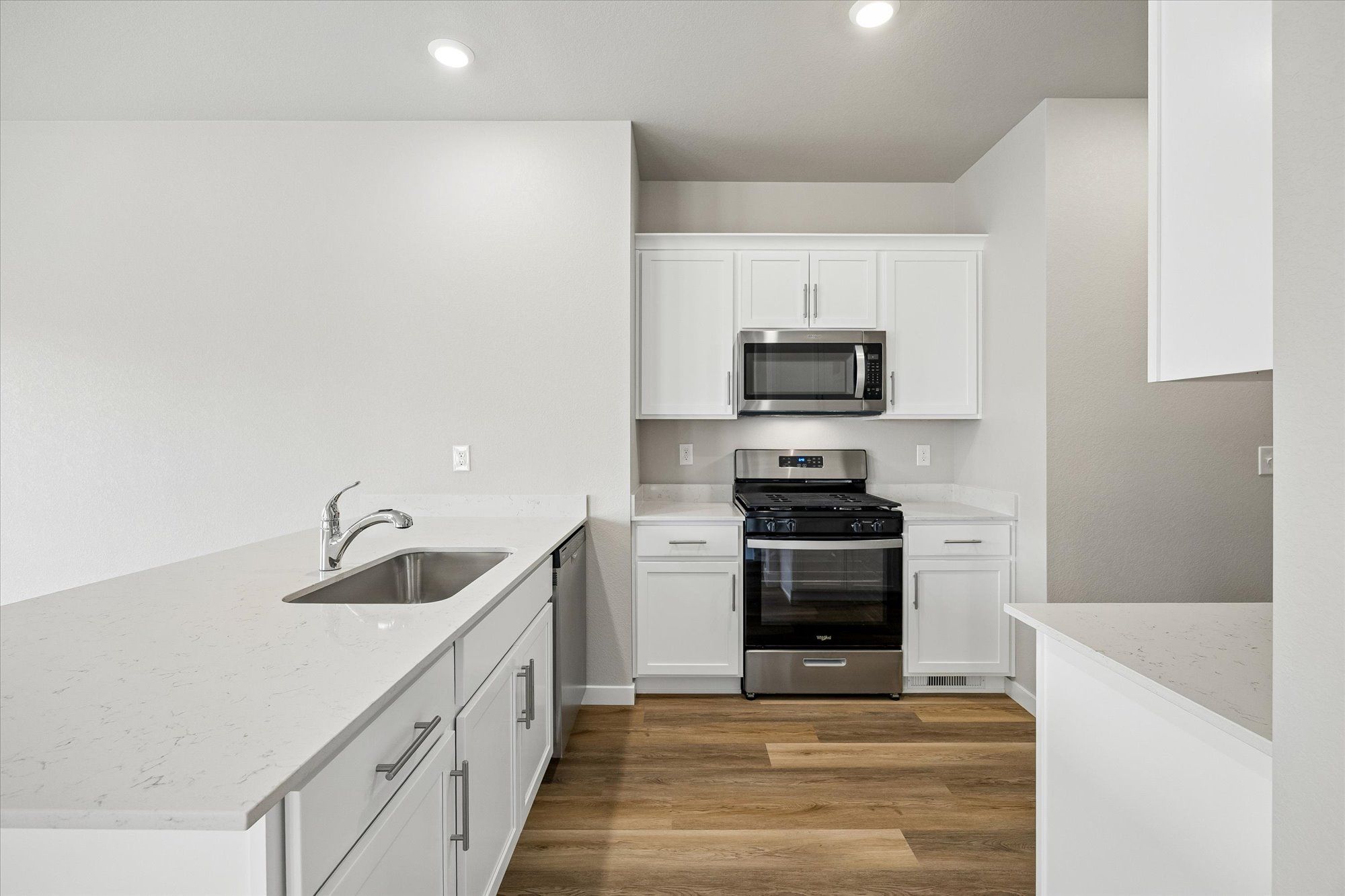 The kitchen has stainless steel appliances and plank flooring.