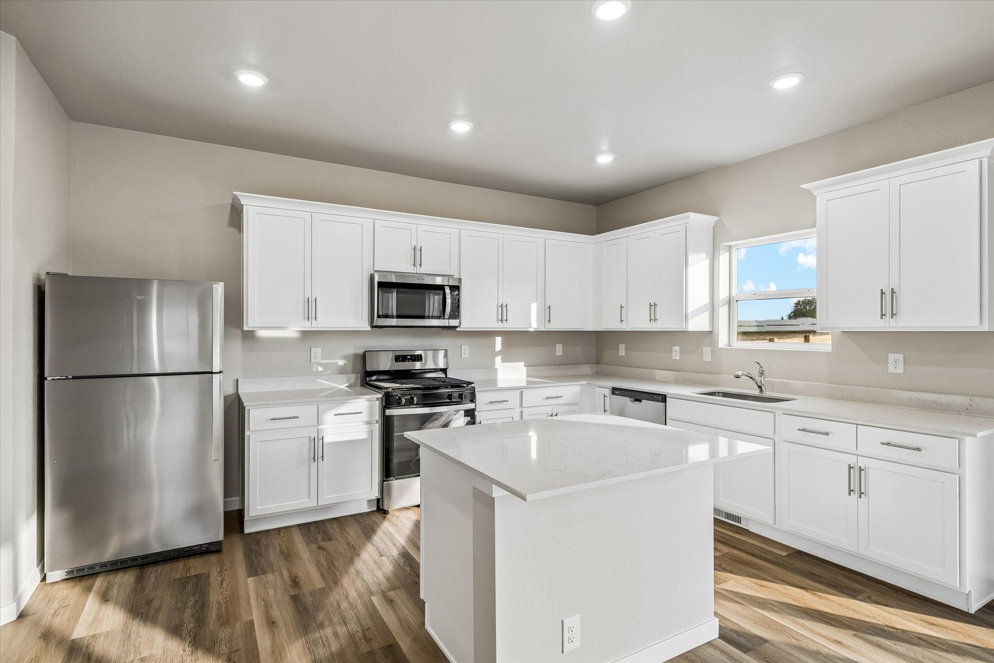The kitchen has stainless steel appliances and plank flooring.