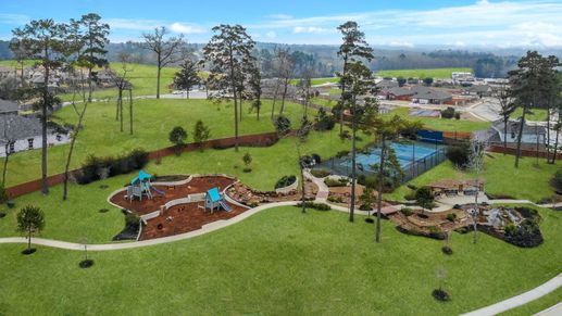 Aerial view of park with playground, tennis court, and covered pergola