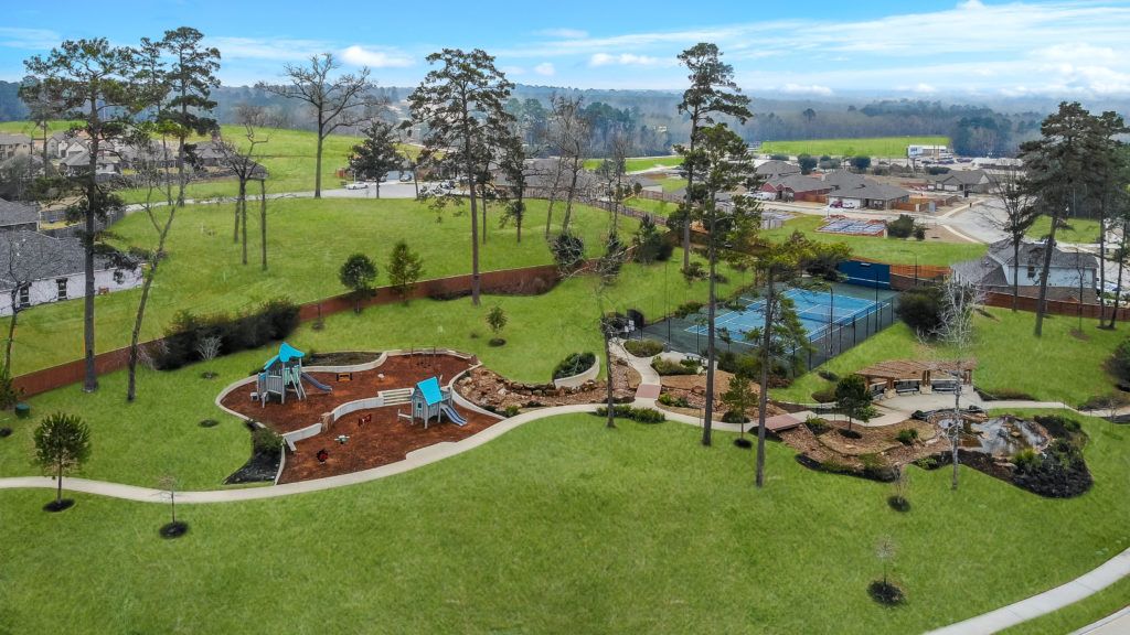 Aerial view of park with playground, tennis court, and covered pergola