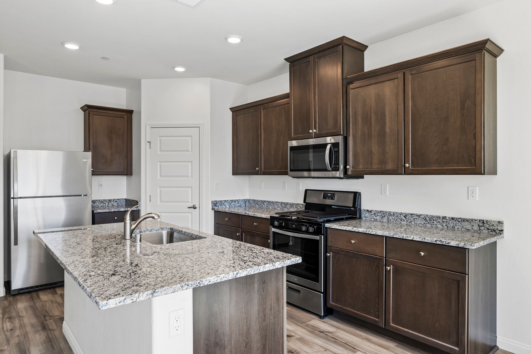 The kitchen has beautiful granite countertops and plank flooring.