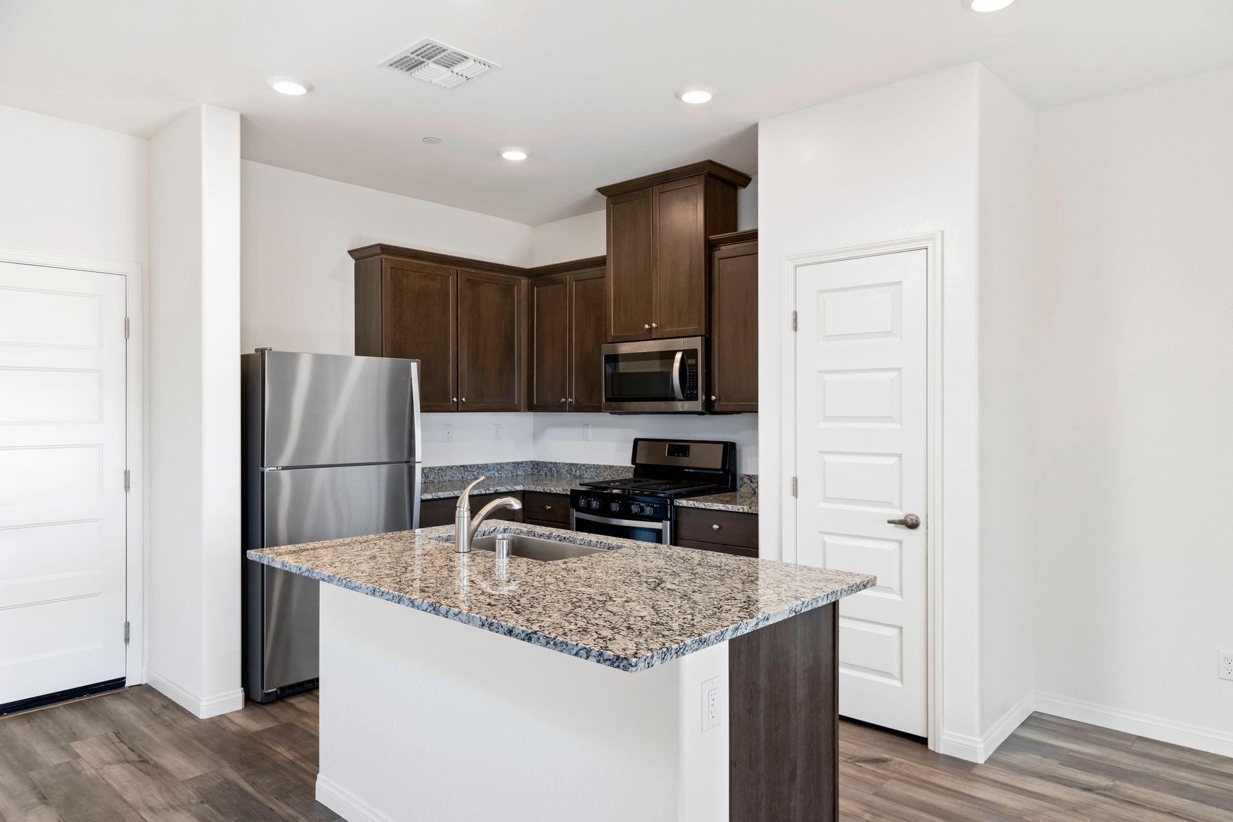 The kitchen has beautiful granite countertops and plank flooring.