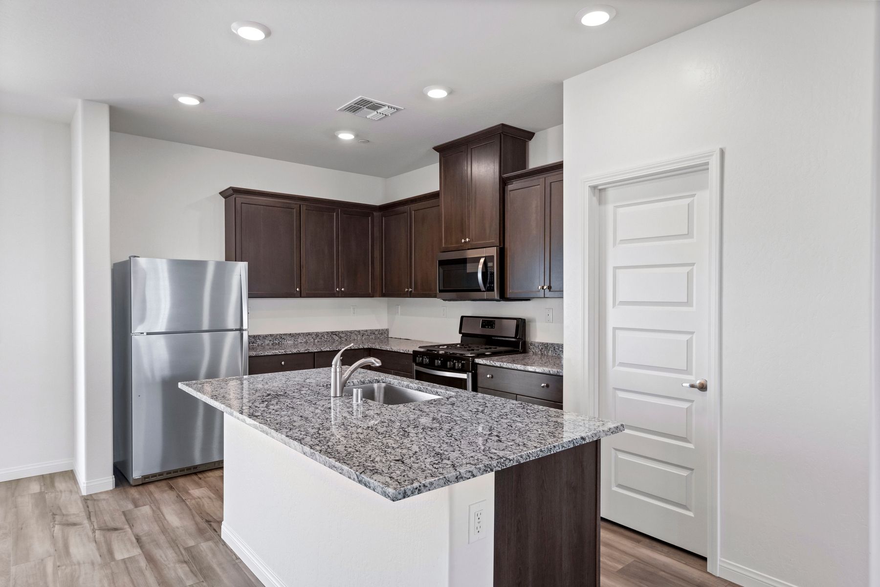 The kitchen has beautiful granite countertops and plank flooring.