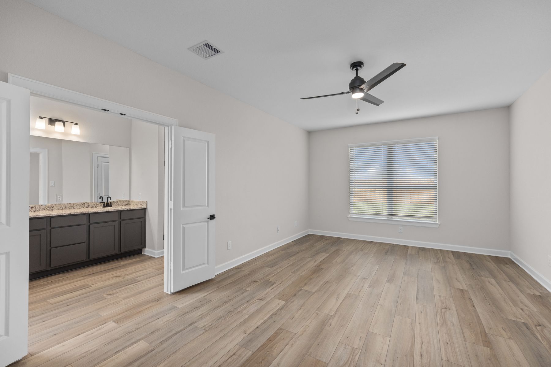 The master bedroom has plank flooring and a ceiling fan.