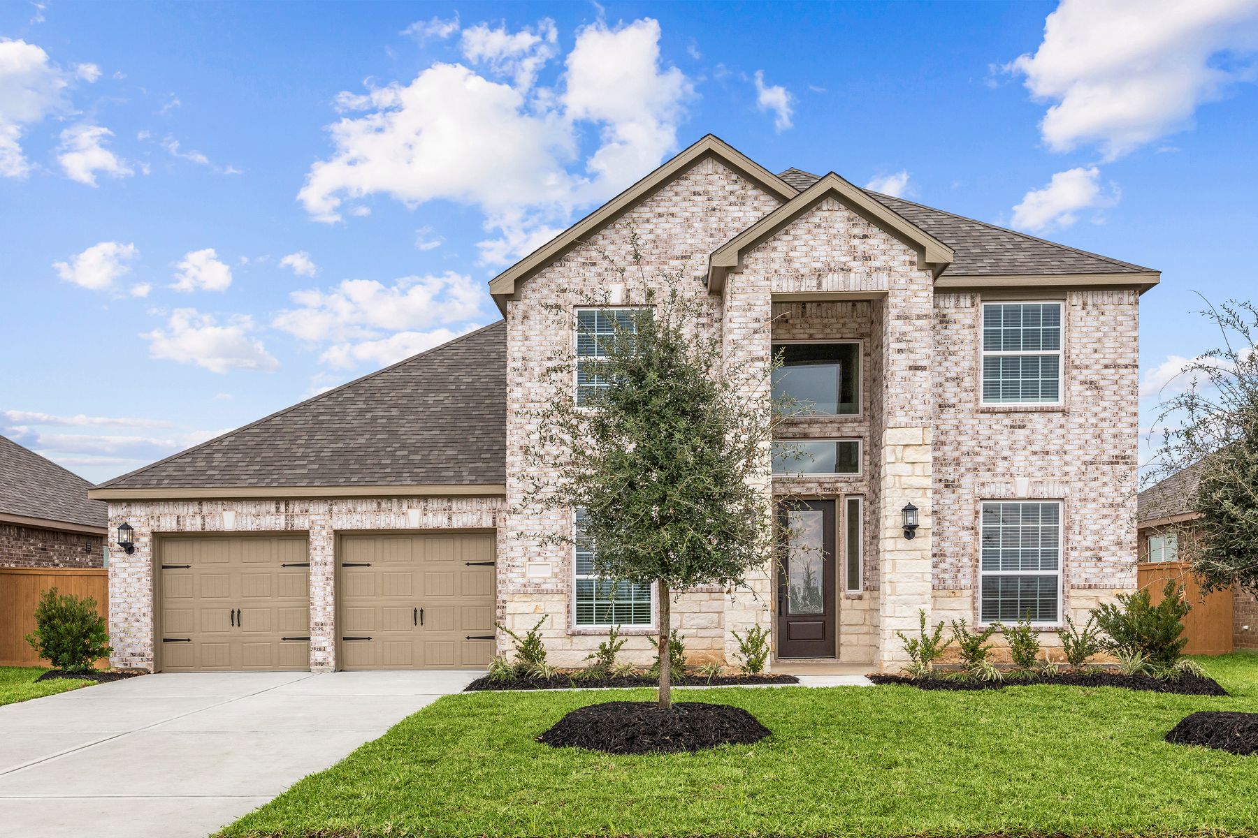 The Redwood is a two story home with brick and front yard landscaping.