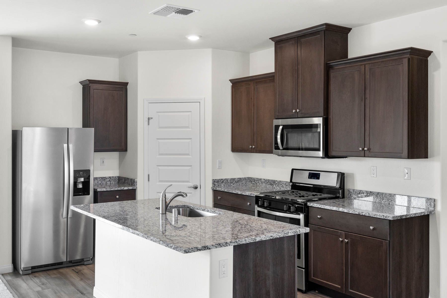 The kitchen has stainless steel appliances and plank flooring.
