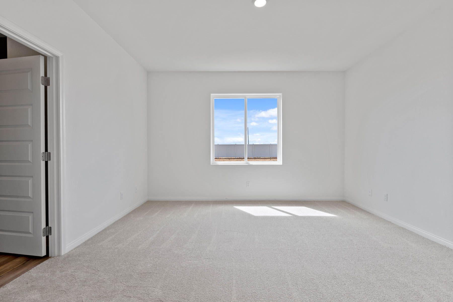 The master bedroom has a large window and carpet.