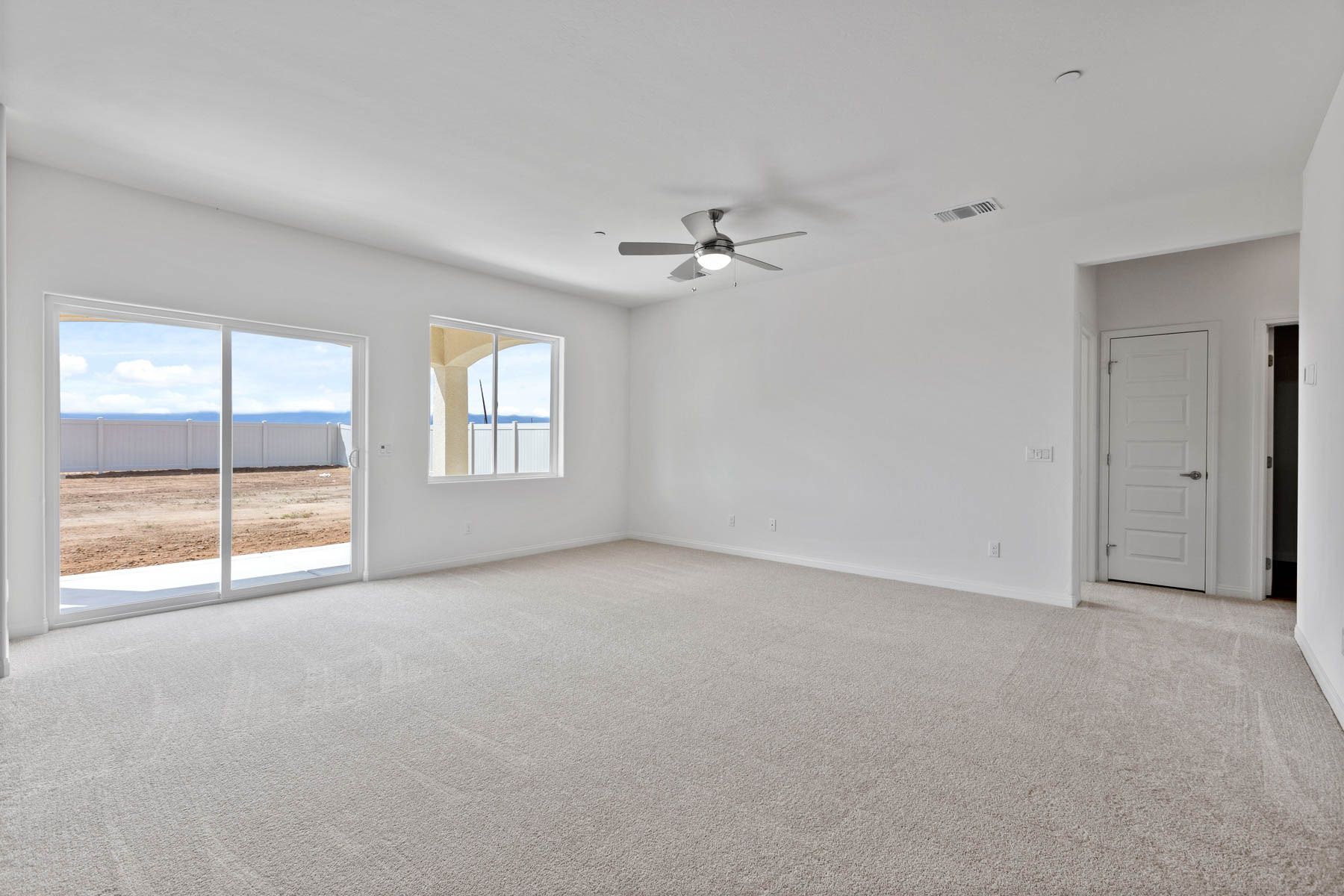 The spacious family room has carpet and a ceiling fan.
