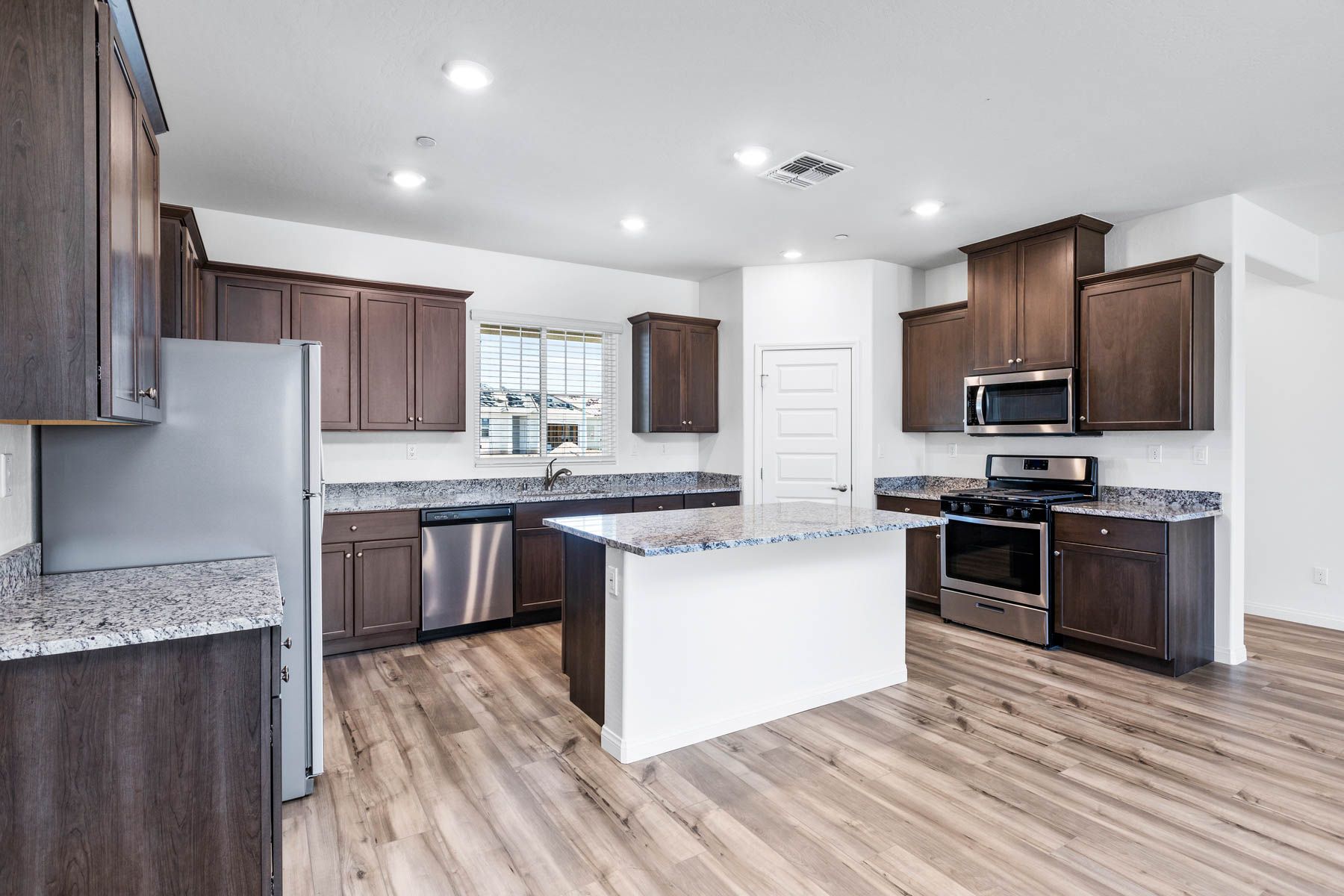 The kitchen has stainless steel appliances and plank flooring.