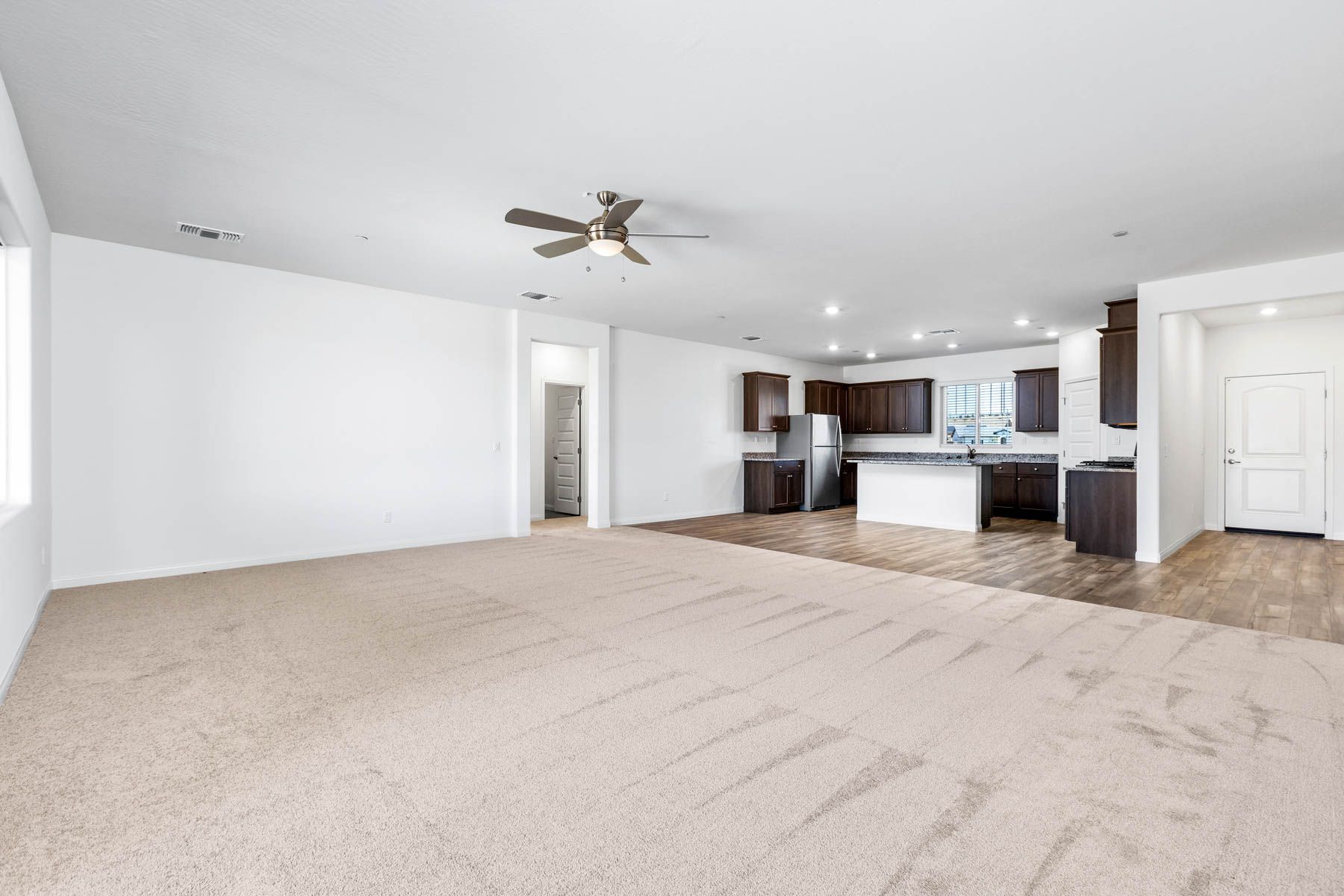The spacious family room has carpet and a ceiling fan.
