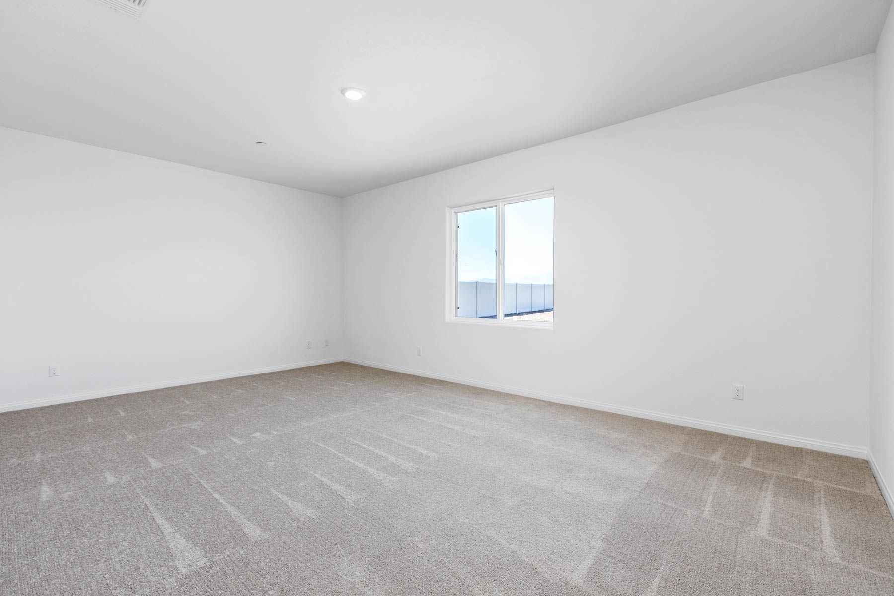 The master bedroom has a large window and carpet.