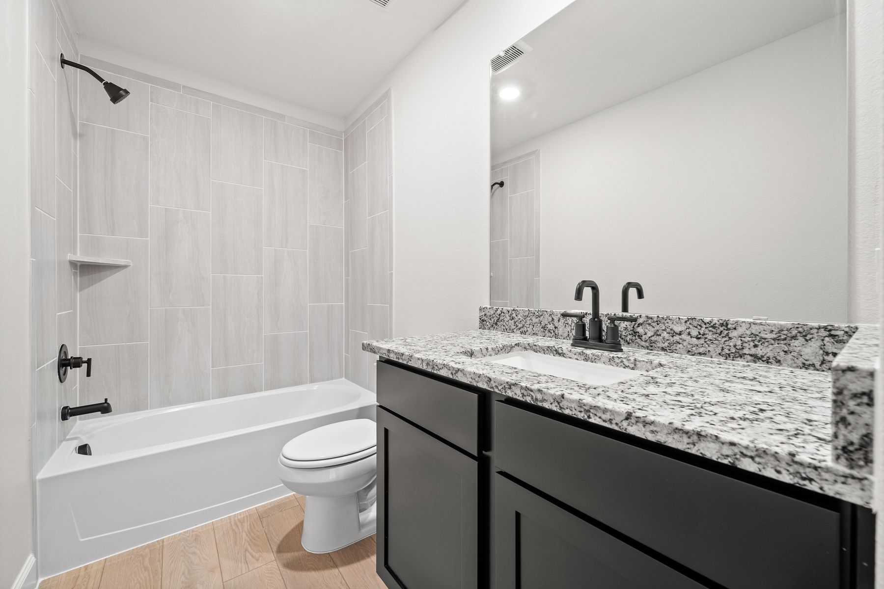 The secondary bathroom of the Yaupon has a beautiful tiled shower-tub combo.