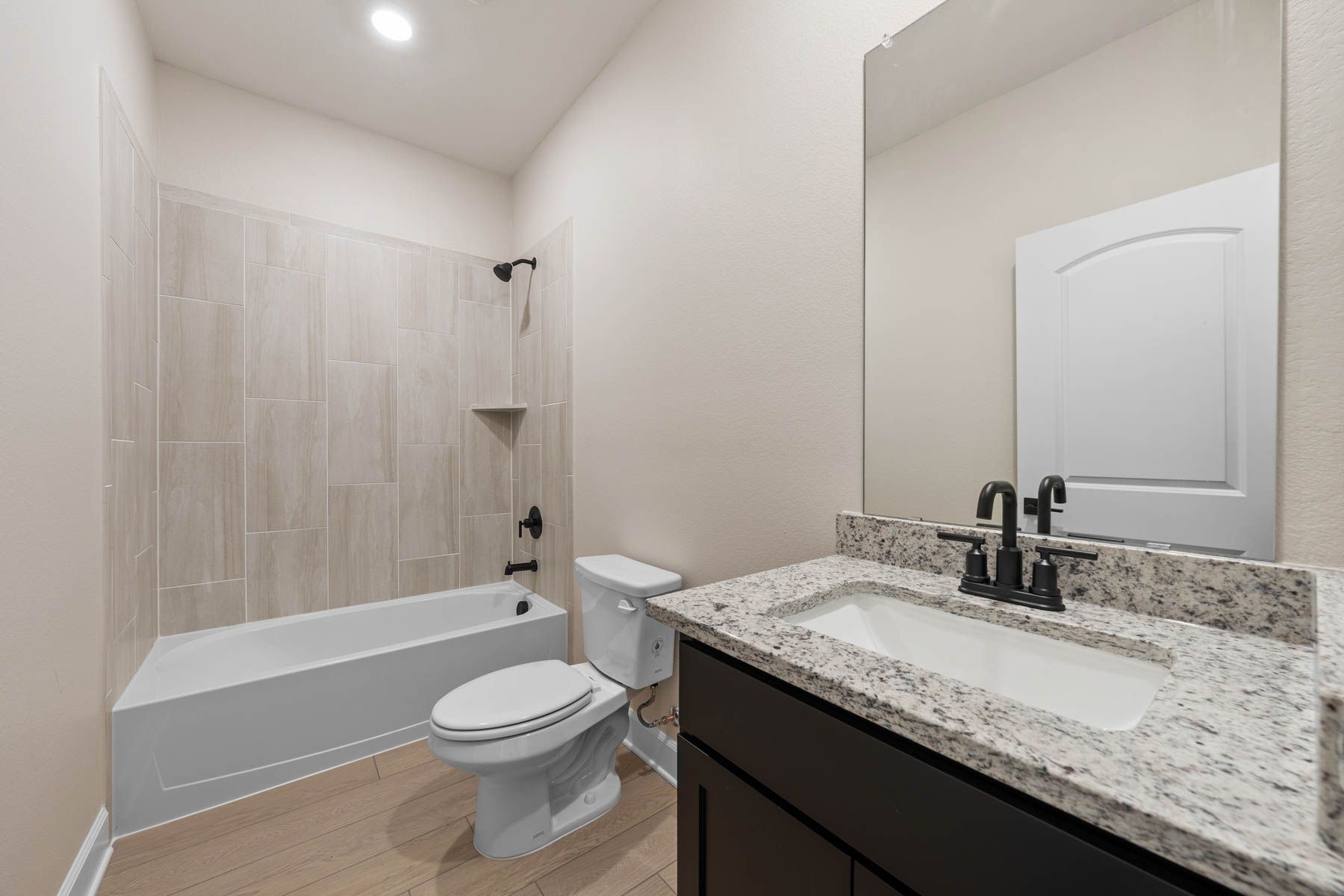 The secondary bathroom has a spacious vanity area and a tiled shower-tub combo.