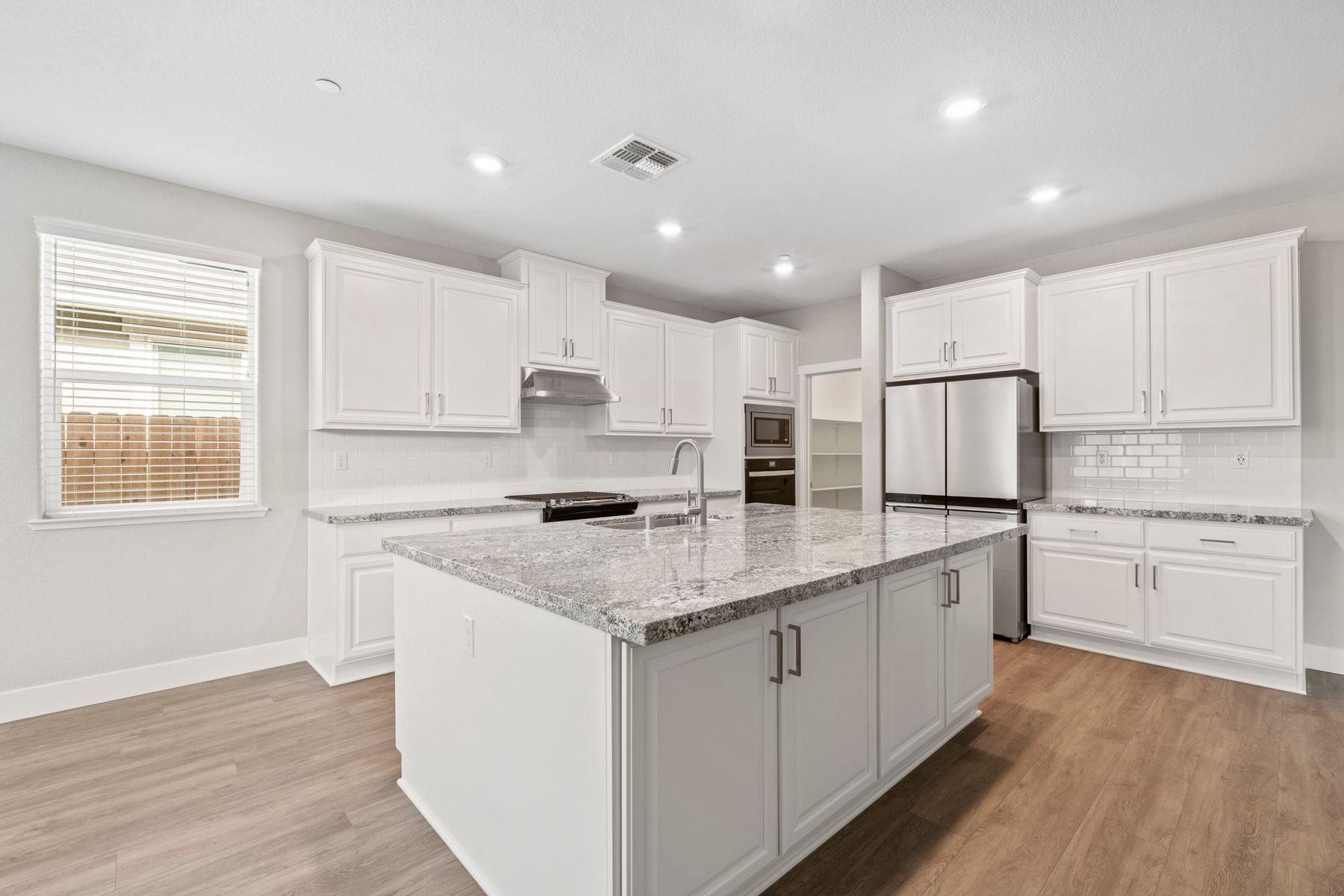 The kitchen has beautiful white cabinets and granite countertops.