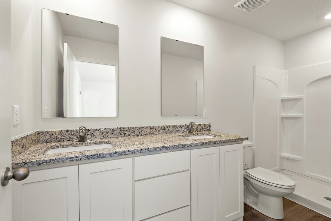 The master bathroom has a dual sink vanity and step in shower. 