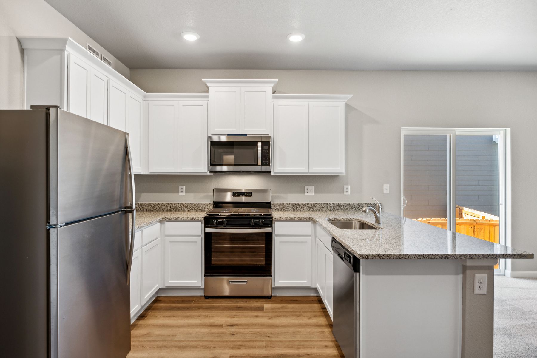 The kitchen has stainless appliances and plank flooring.
