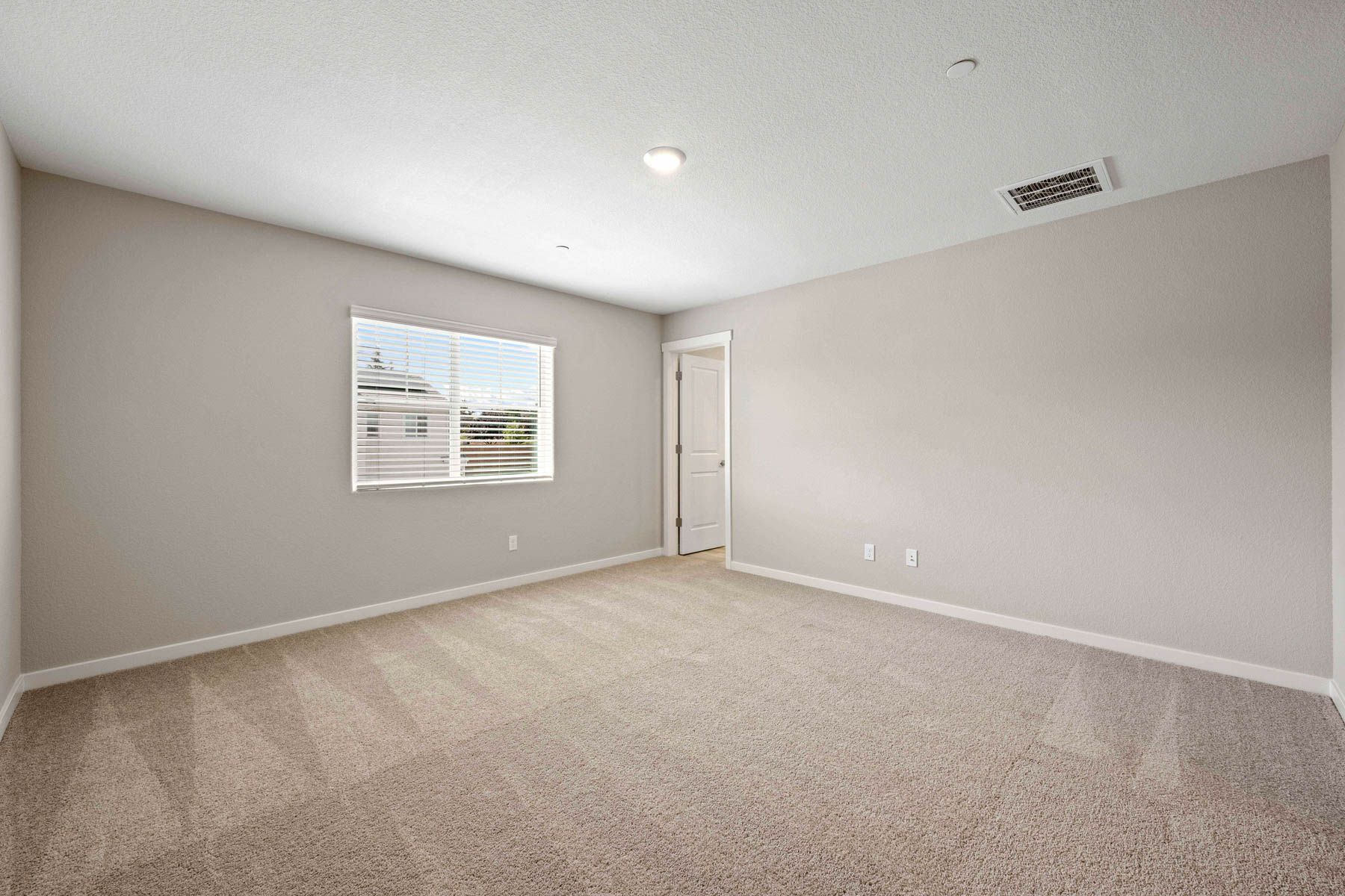 The master bedroom has a large window and carpet.