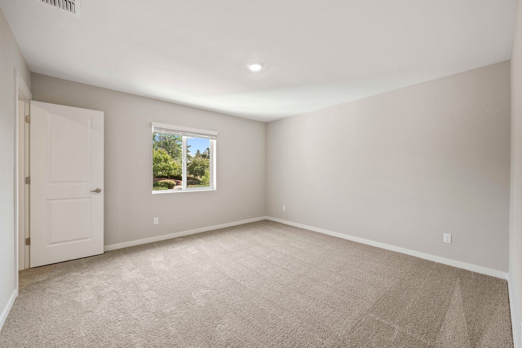 The master bedroom has a large window and carpet.