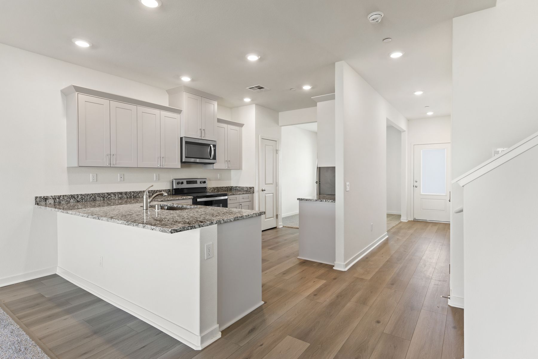The kitchen has stainless steel appliances and plank flooring.