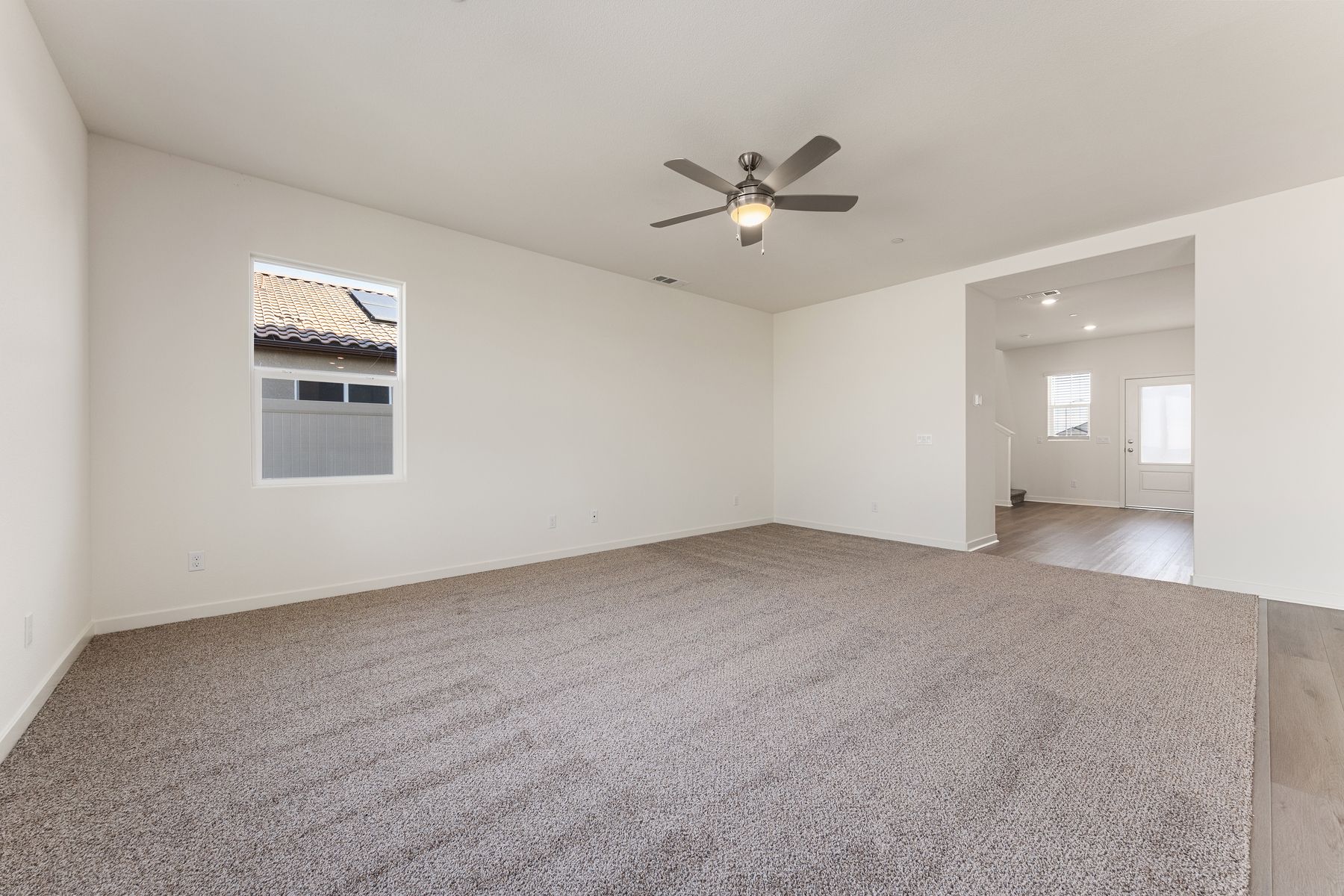 The family room is connected to the foyer and kitchen and has a ceiling fan.
