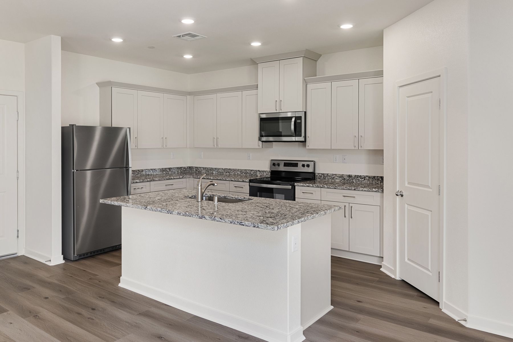 The kitchen has beautiful quartz counters and white cabinets.