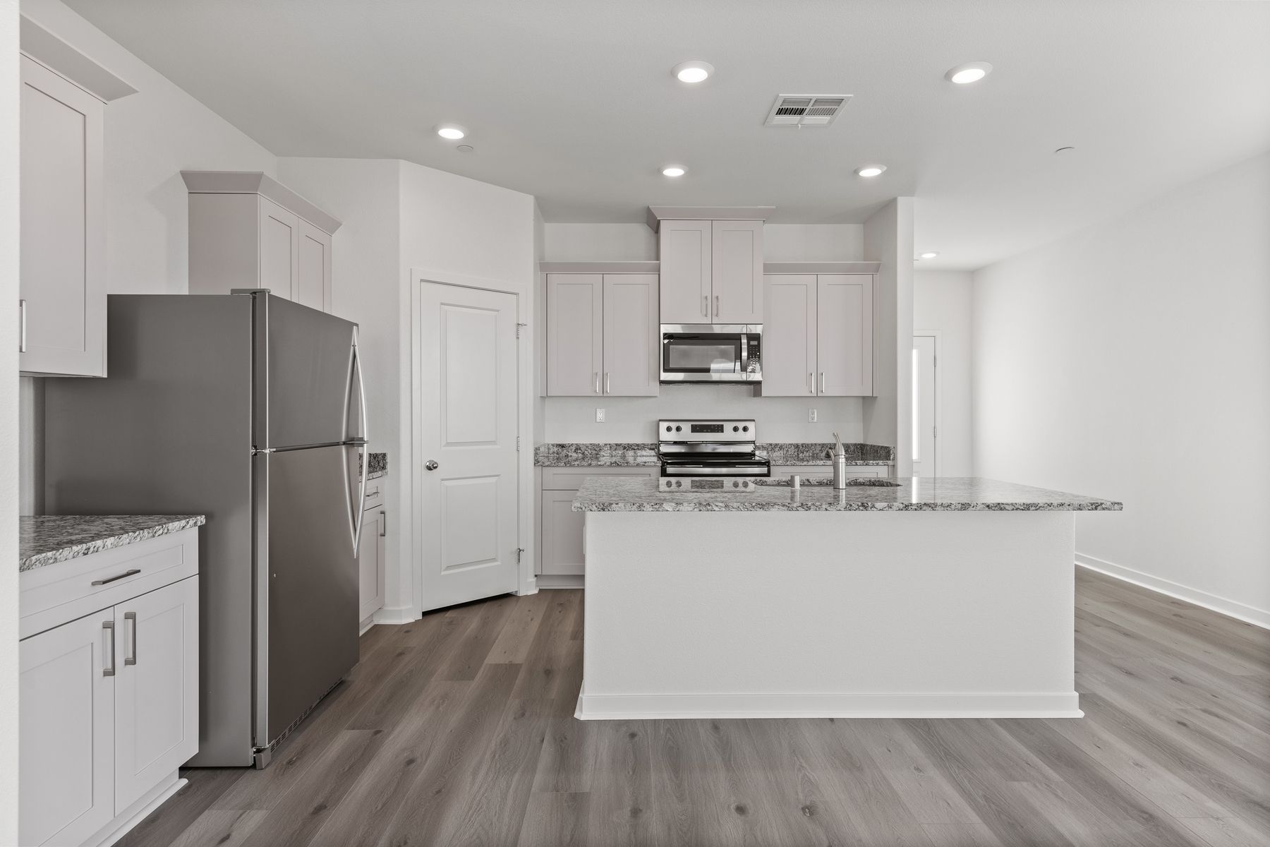 The kitchen has plank flooring and stainless steel appliances.