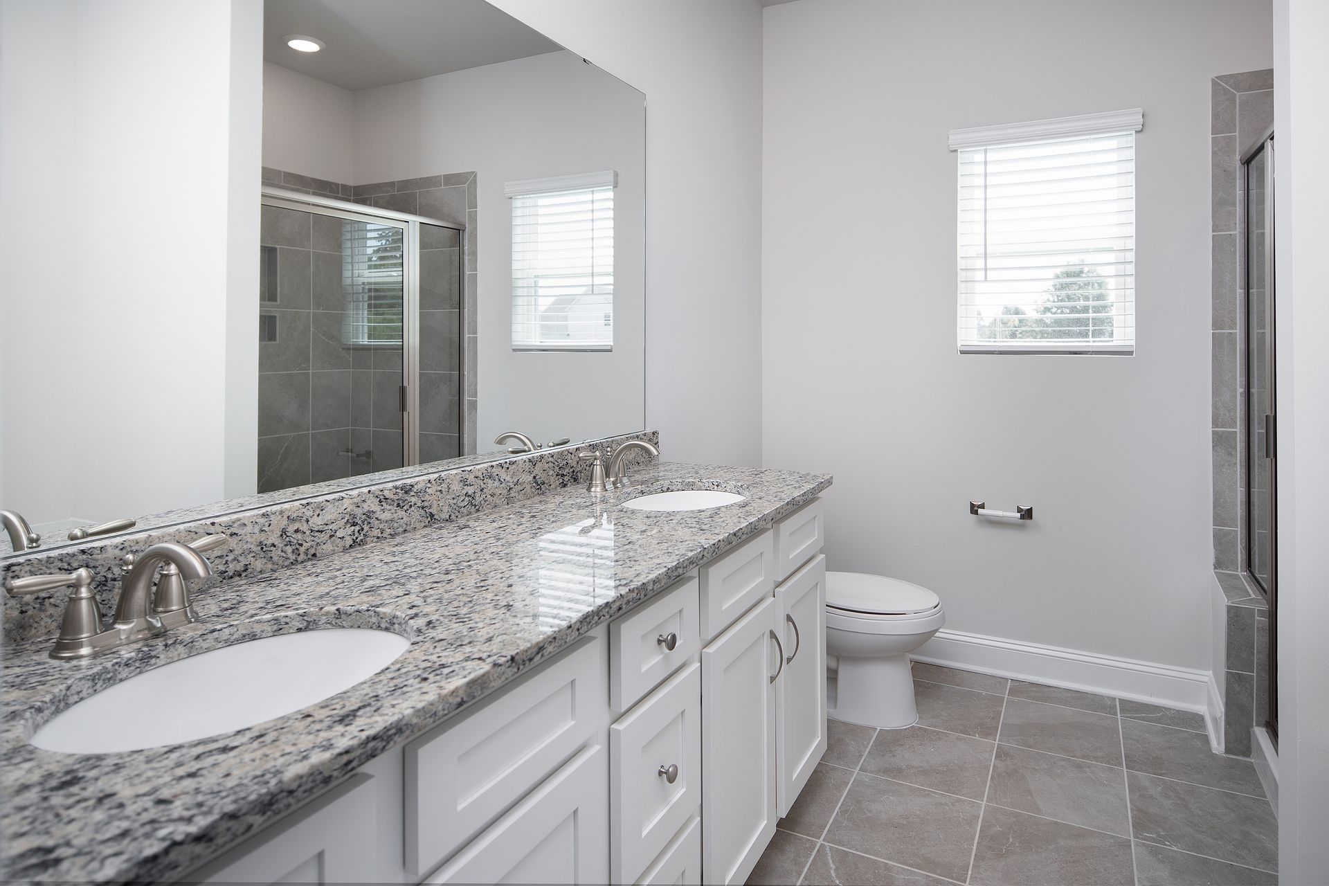 This bathroom offers dual vanities and granite countertops