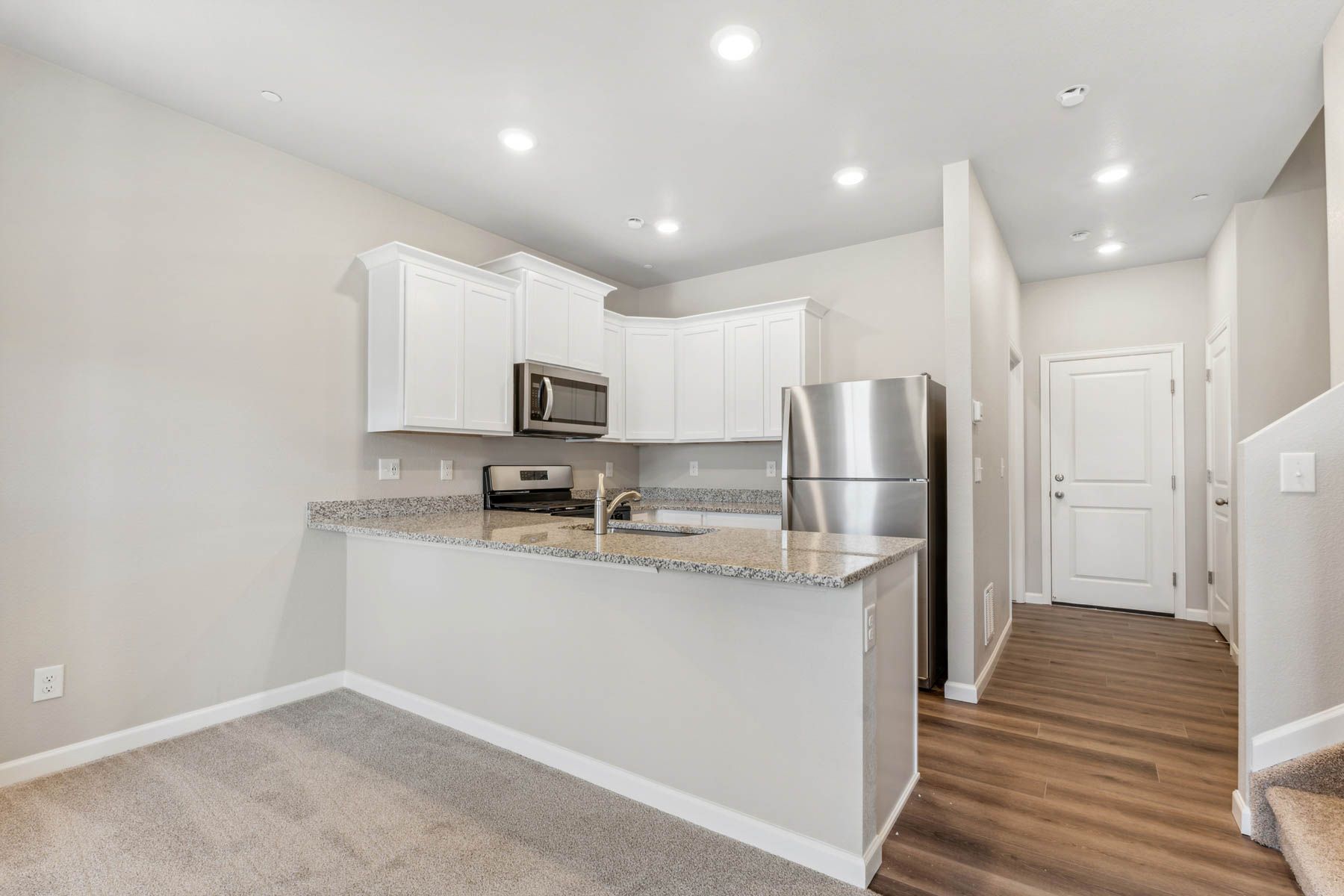 The kitchen has stainless steel appliances and plank flooring.